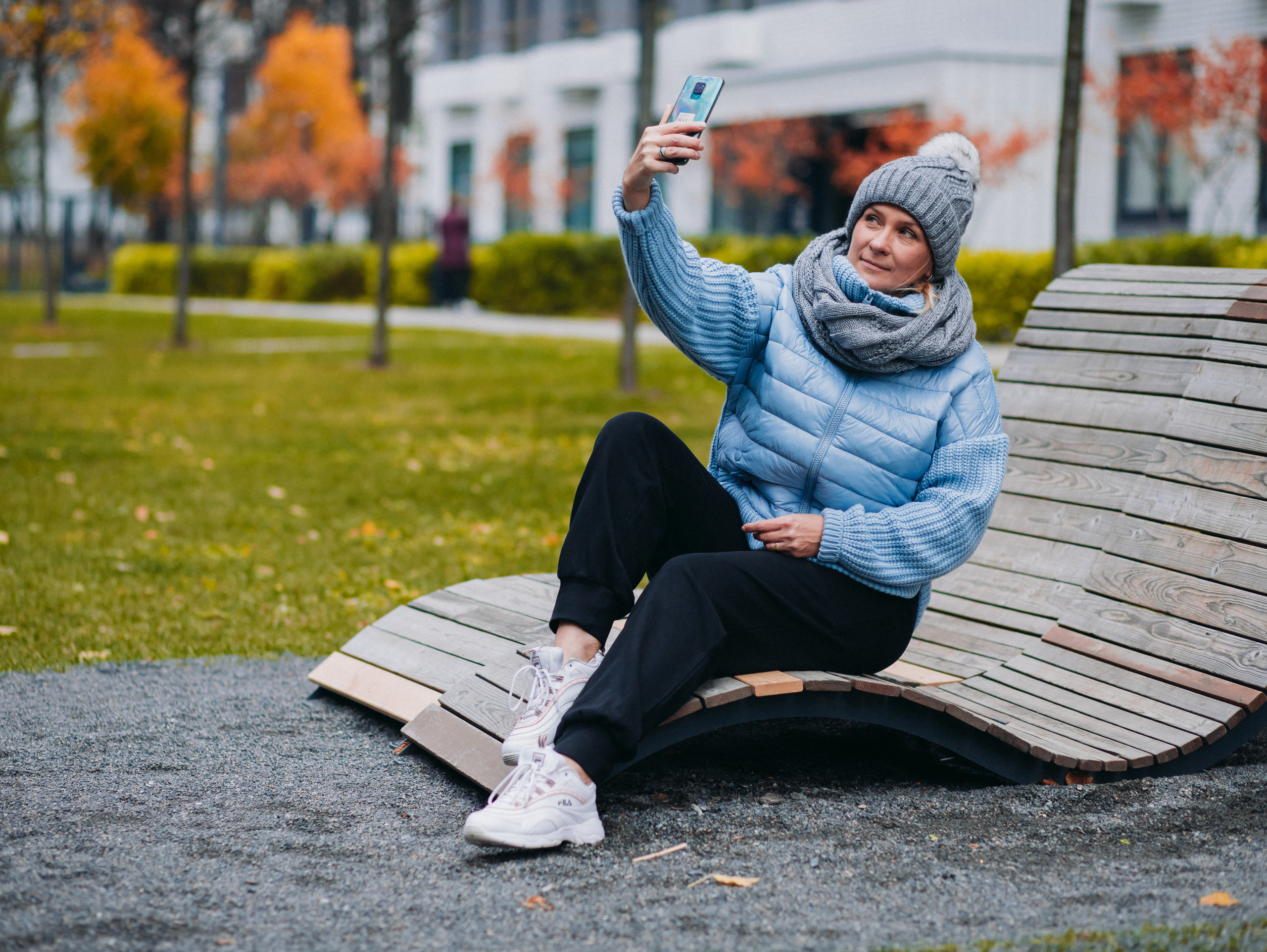 Девушка в шапке и голубой куртке делает селфи