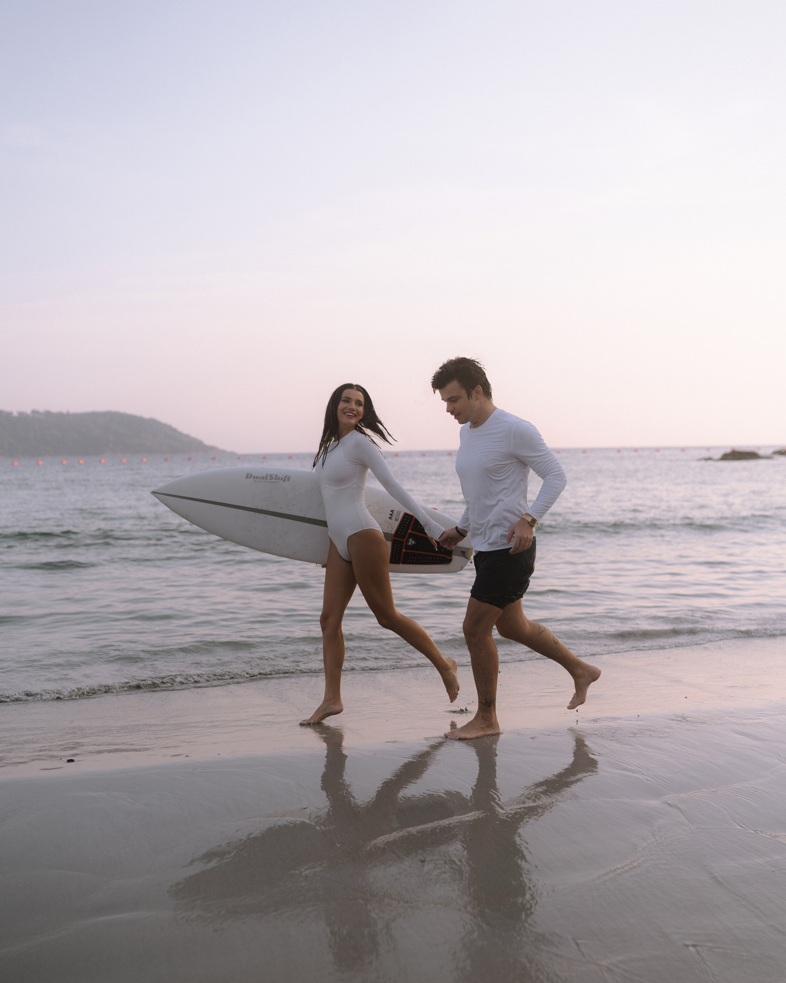 Пара бежит по мелководью, держась за руки — пляжная серия