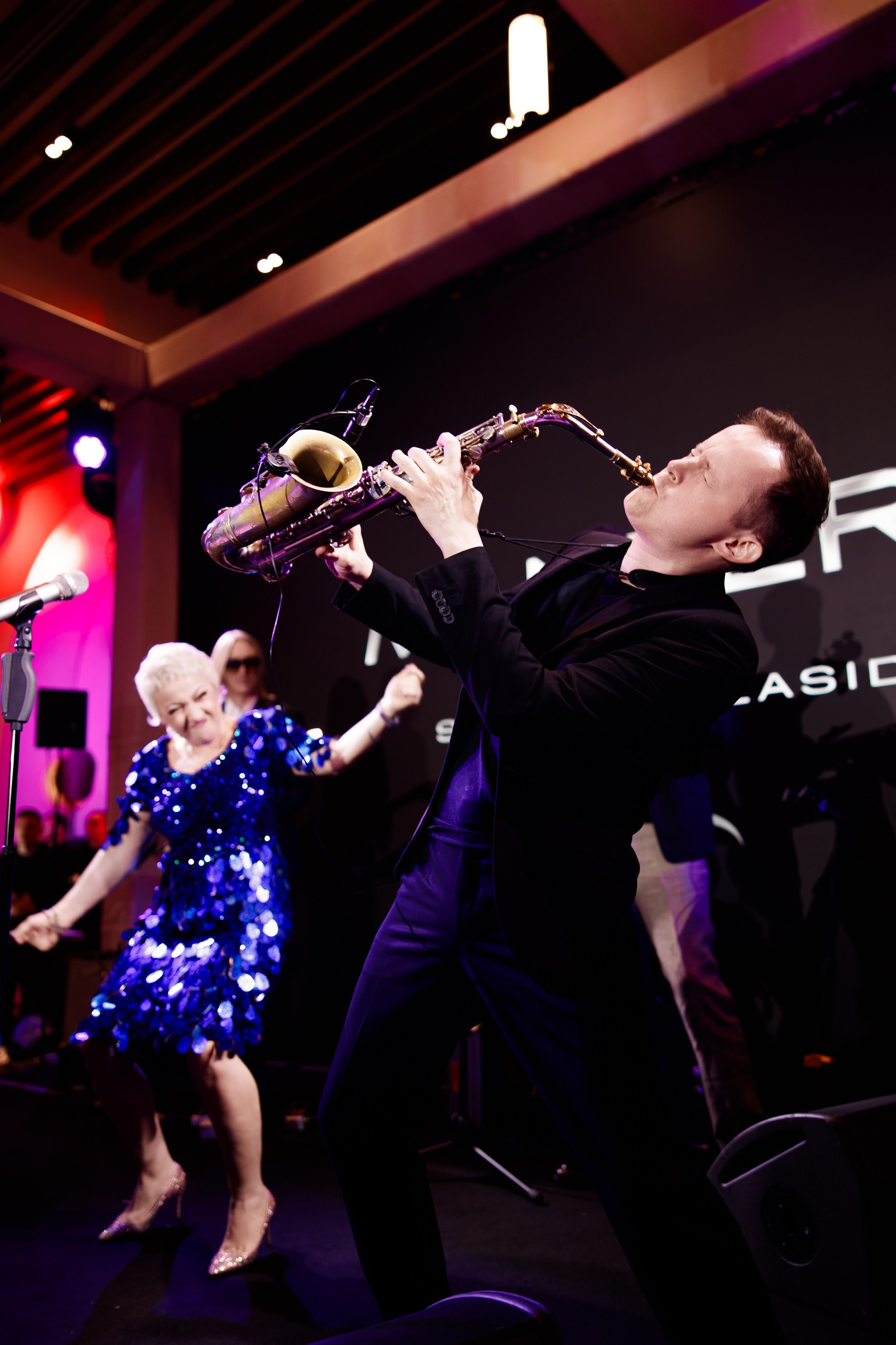 Саксофонист: Музыкант в костюме исполняет джазовую композицию на фоне логотипа Mantera.