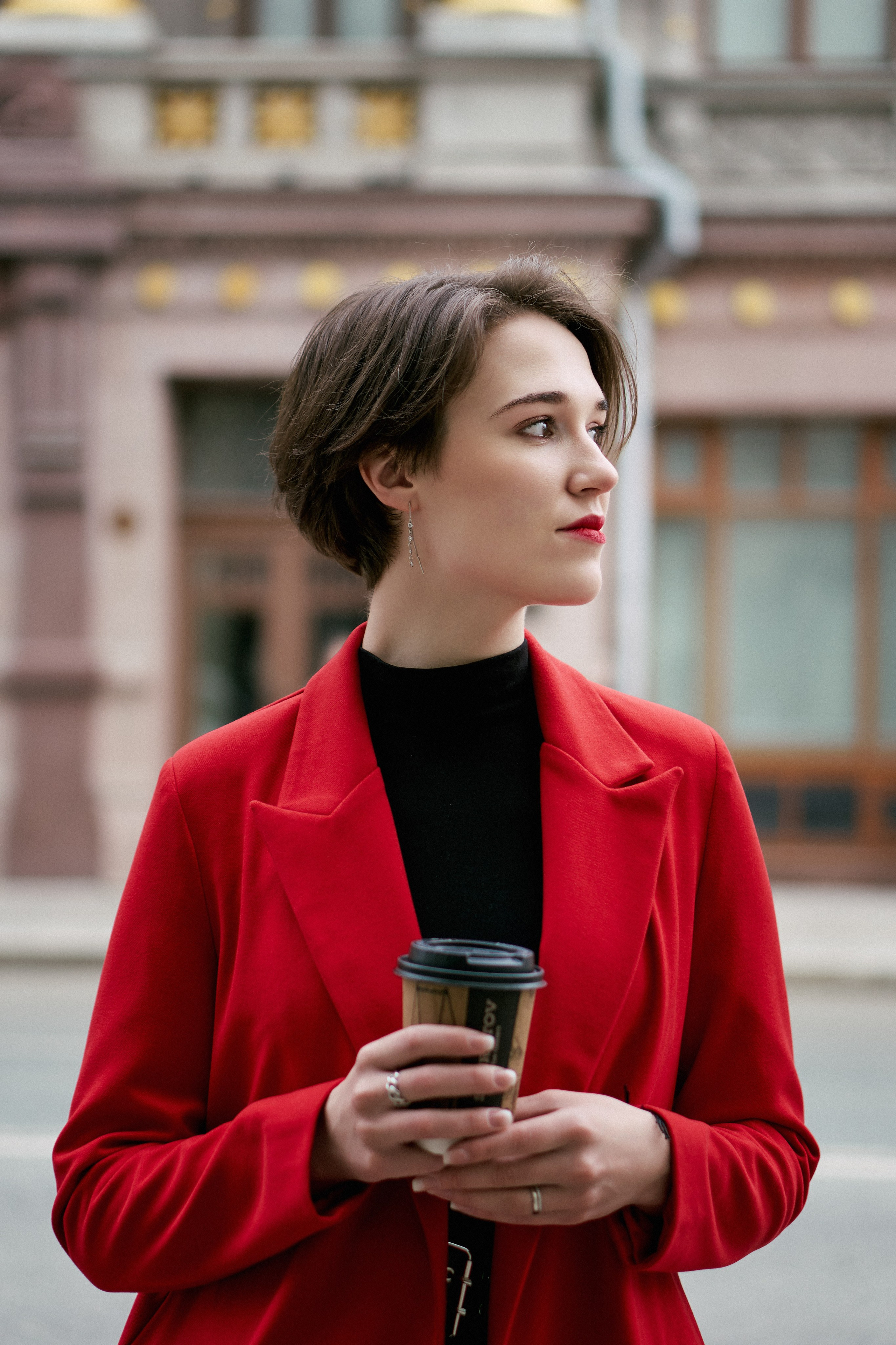 Девушка в красном пиджаке стоит у дороги