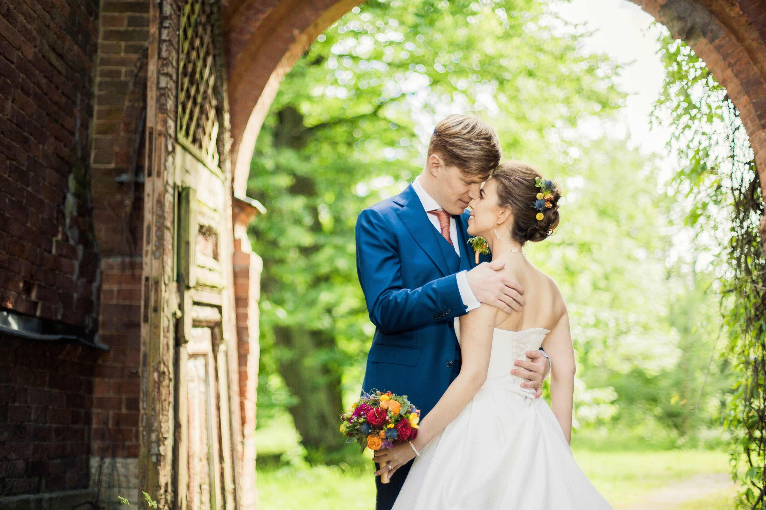жених обнимает невесту под сводом арки ворот в усадьбе Знаменка