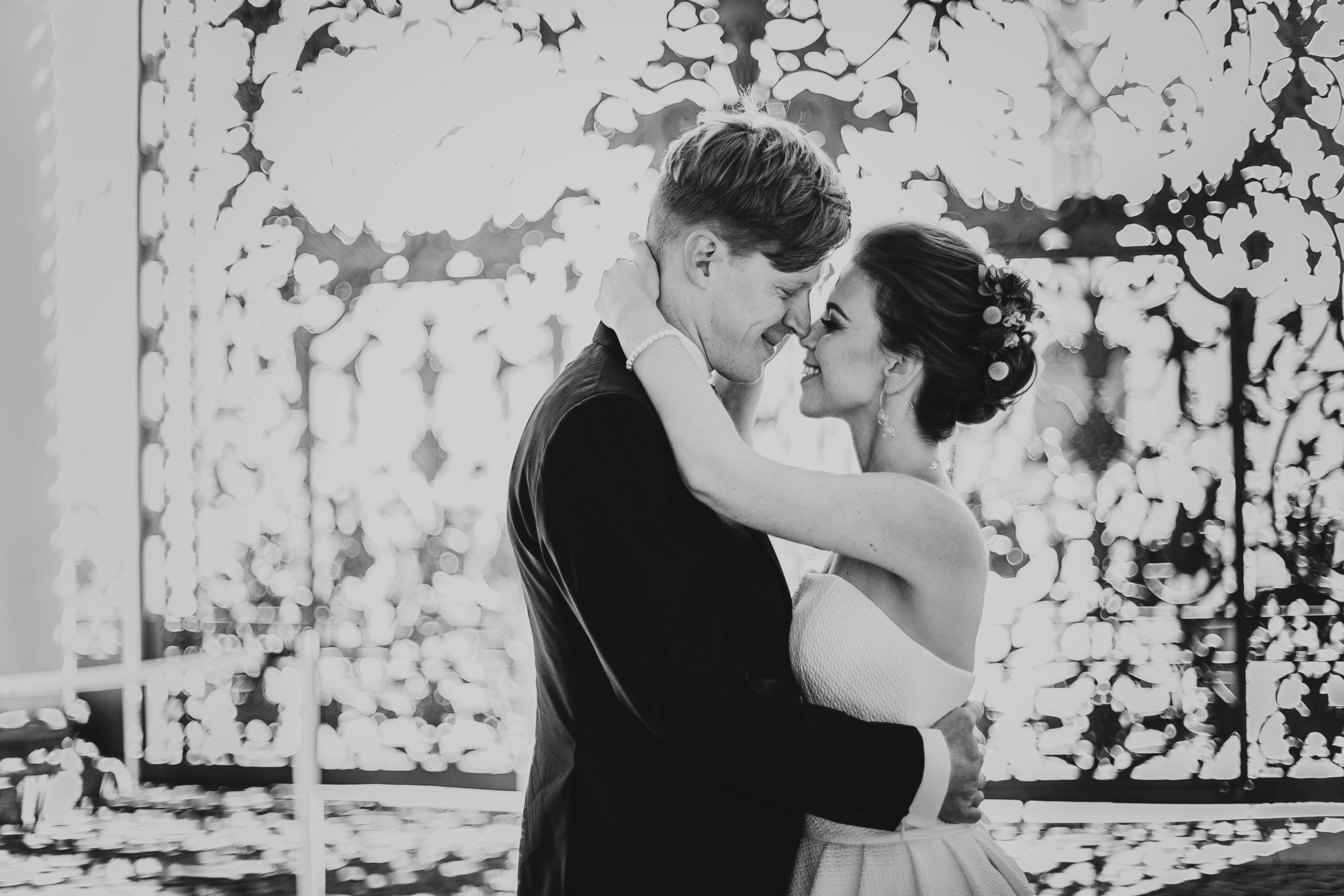 жених и невеста соприкасаются носами на фоне узора решетки старых ворот