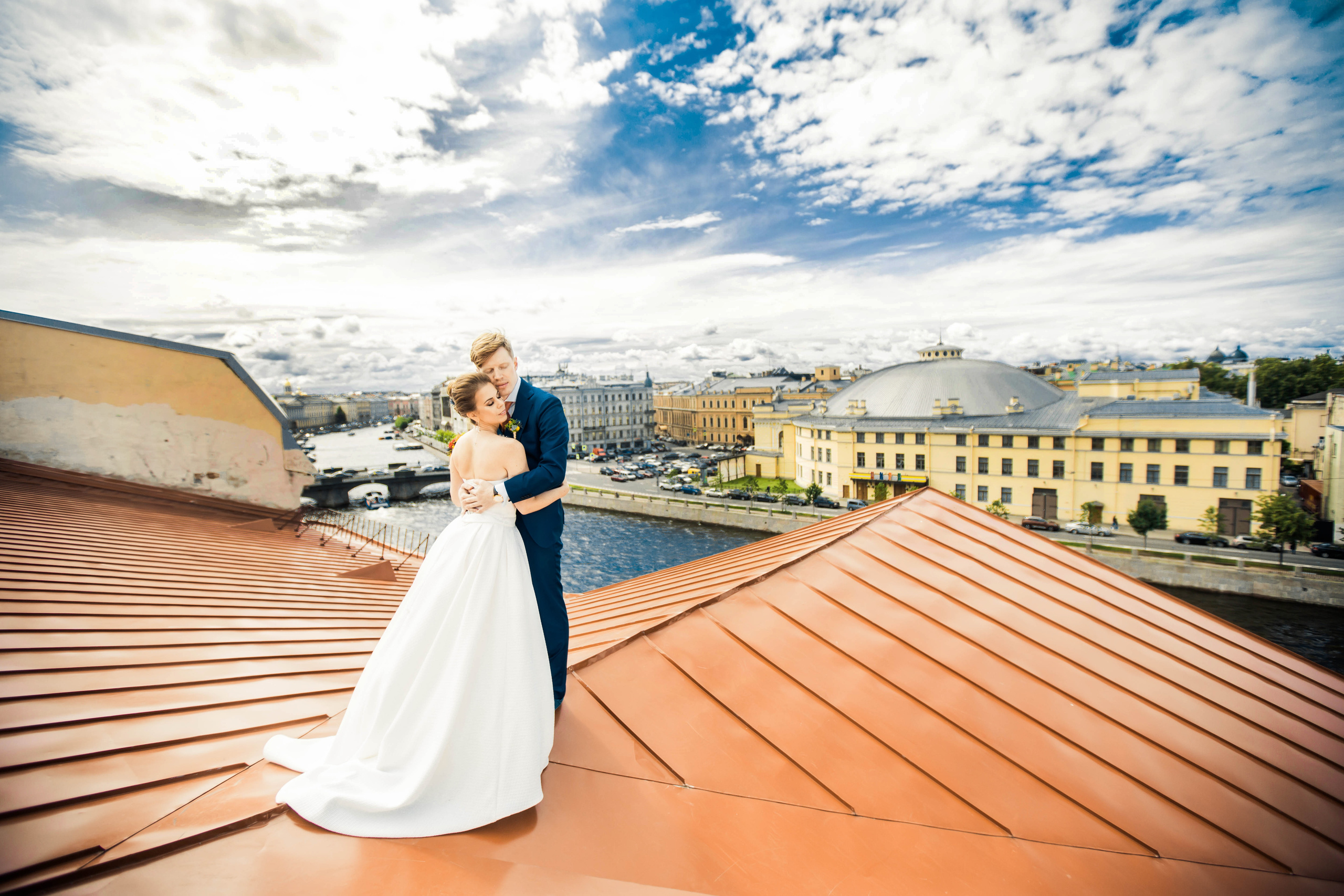 жених обнимает невесту в белом платье на оранжевой крыше на Фонтанке
