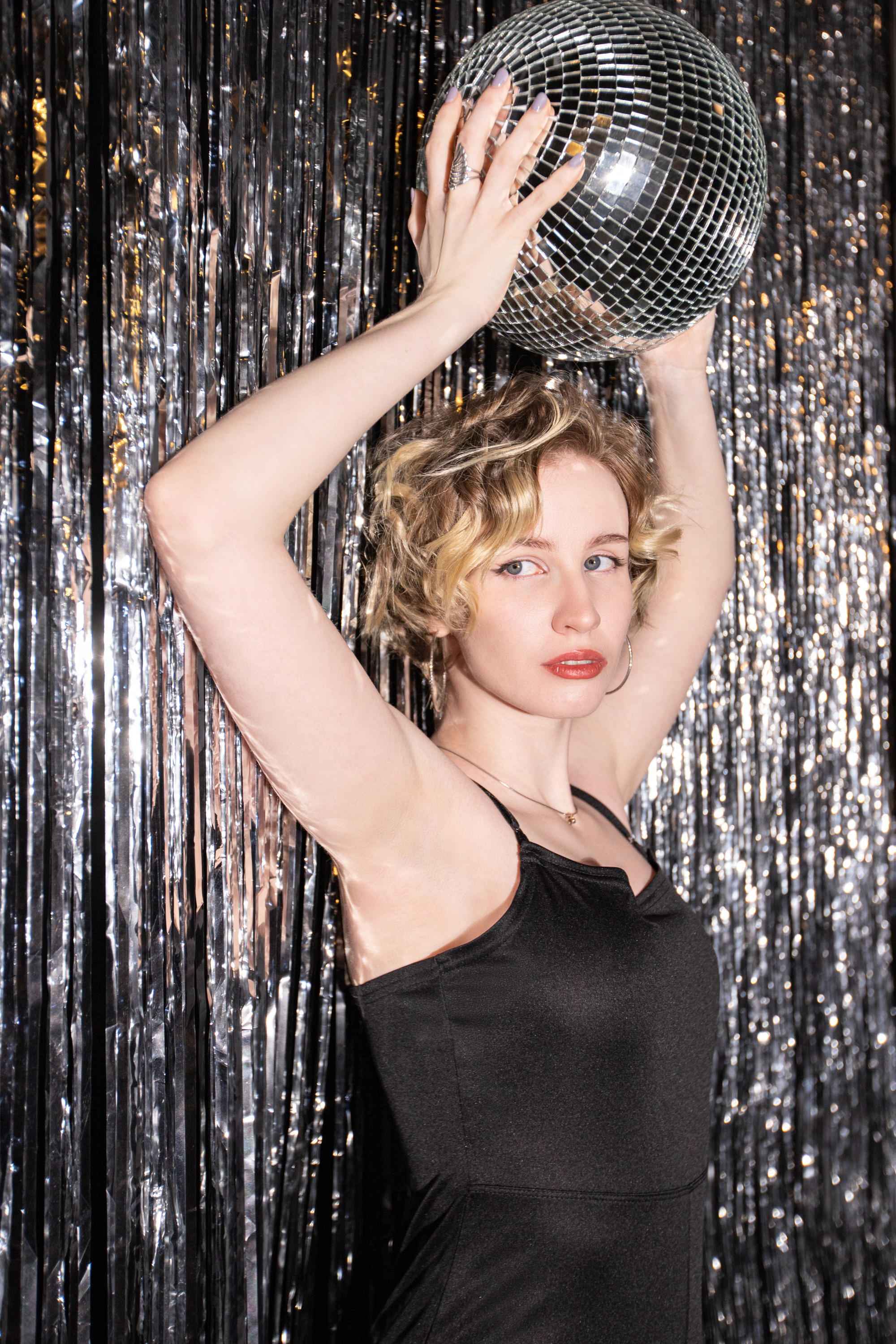 Фотография девушки с диско шаром на фоне новогоднего серебряного  дождика.