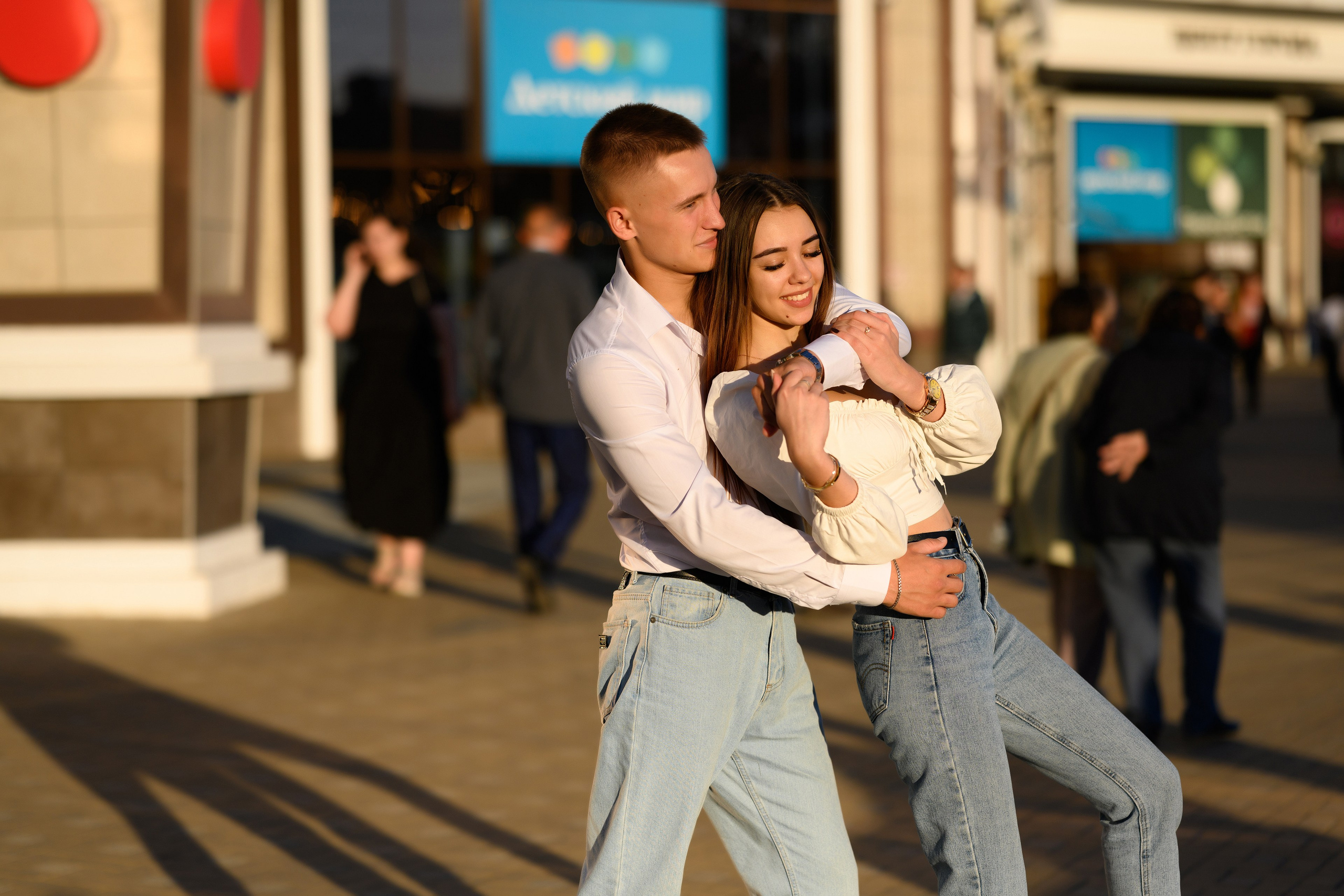 Эмоции в кадре, парень играет с девушкой, обнимает ее на виду у прохожих.