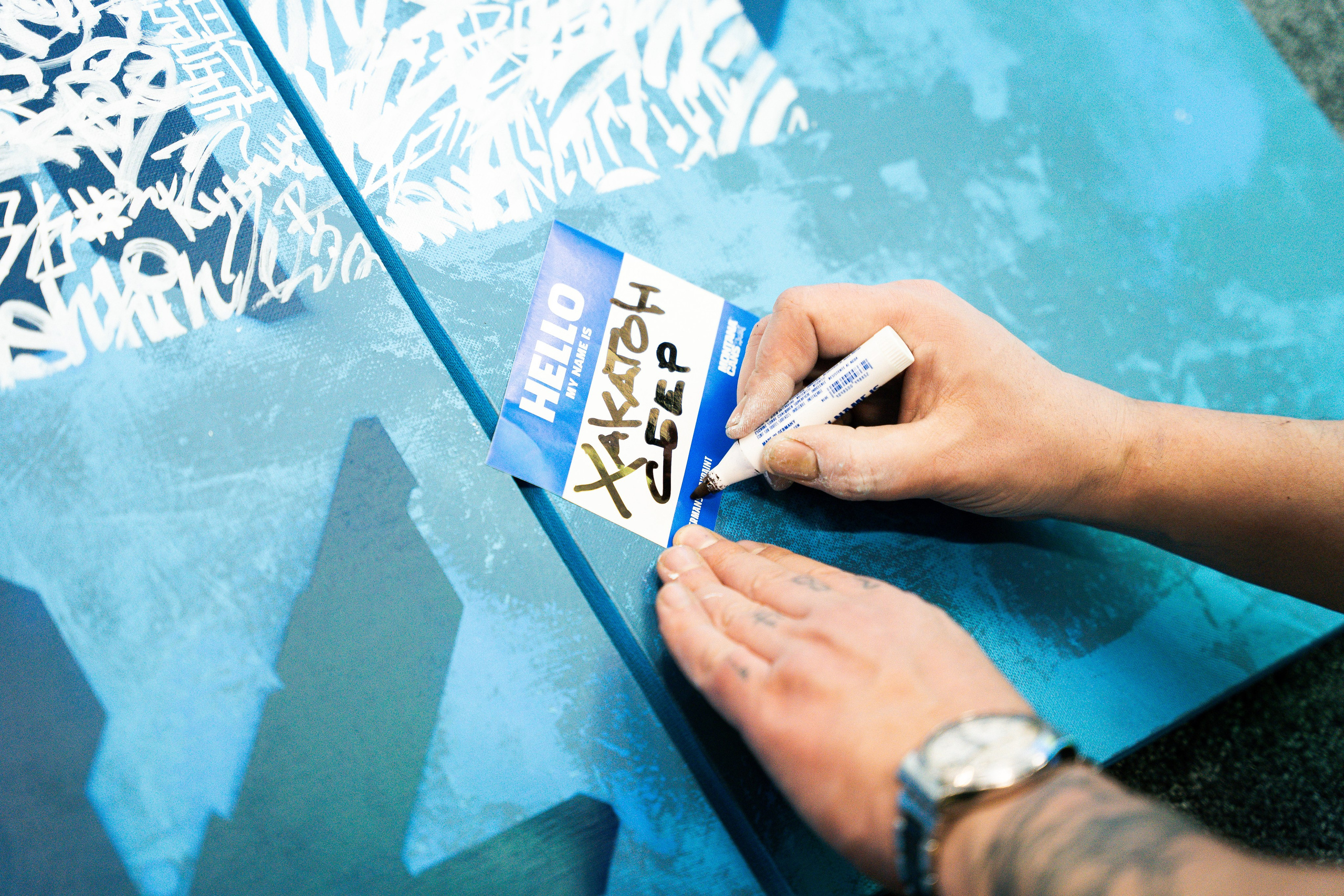 Рука волонтера подписывает badge для участника хакатона