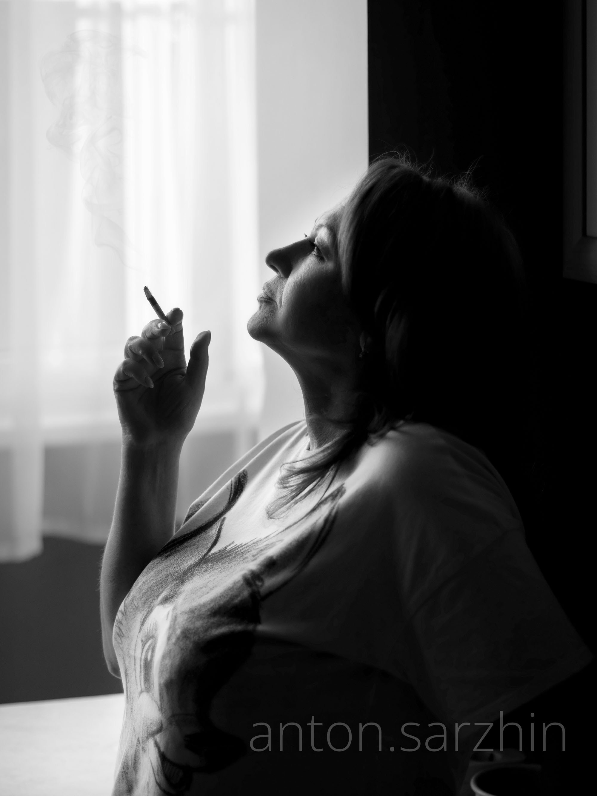 Портрет от света от окна женщина курит