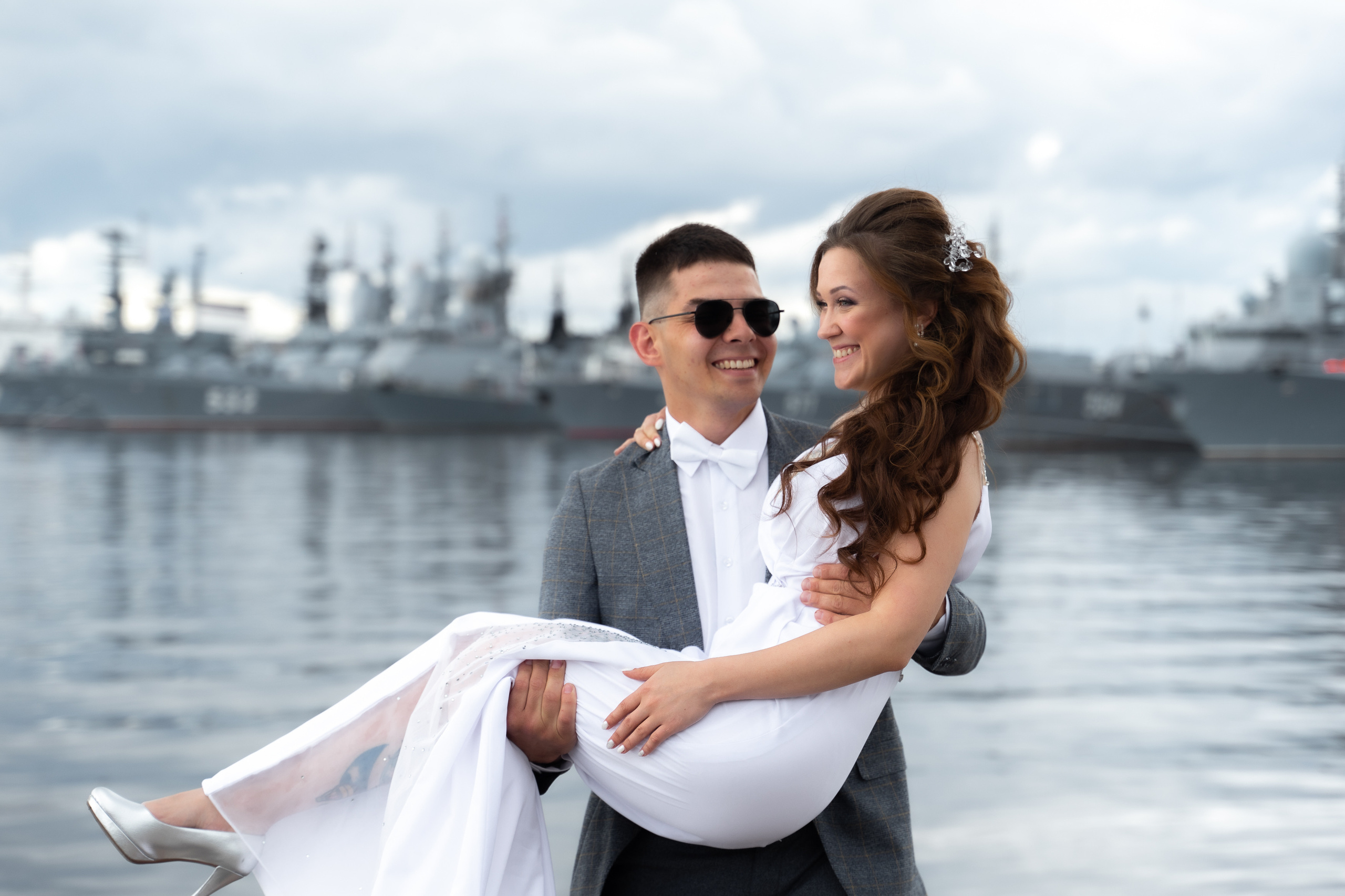 Жених несет на руках невесту по набережной в кронштадте