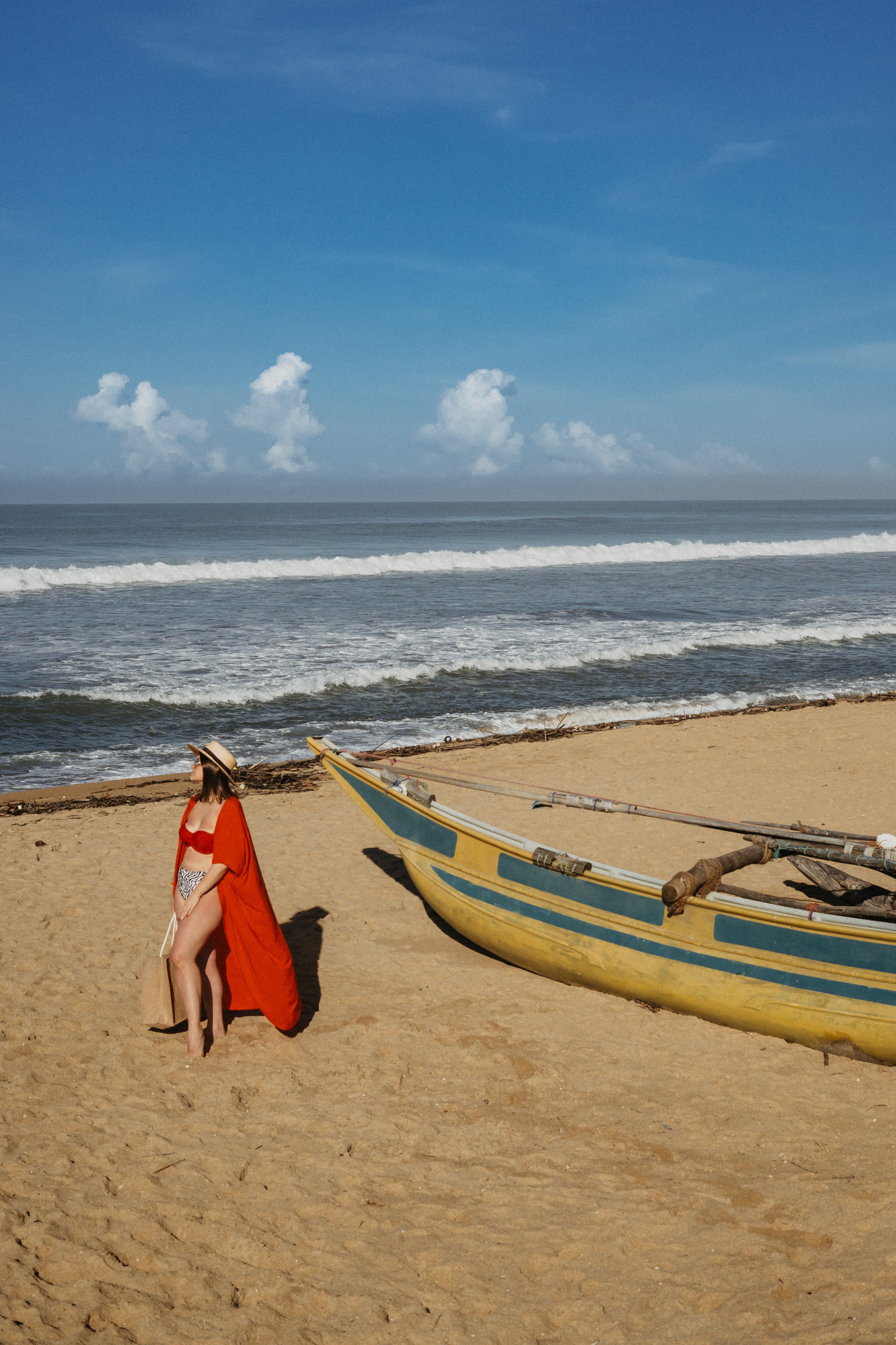 a girl in a straw hat posing on a sandy beach