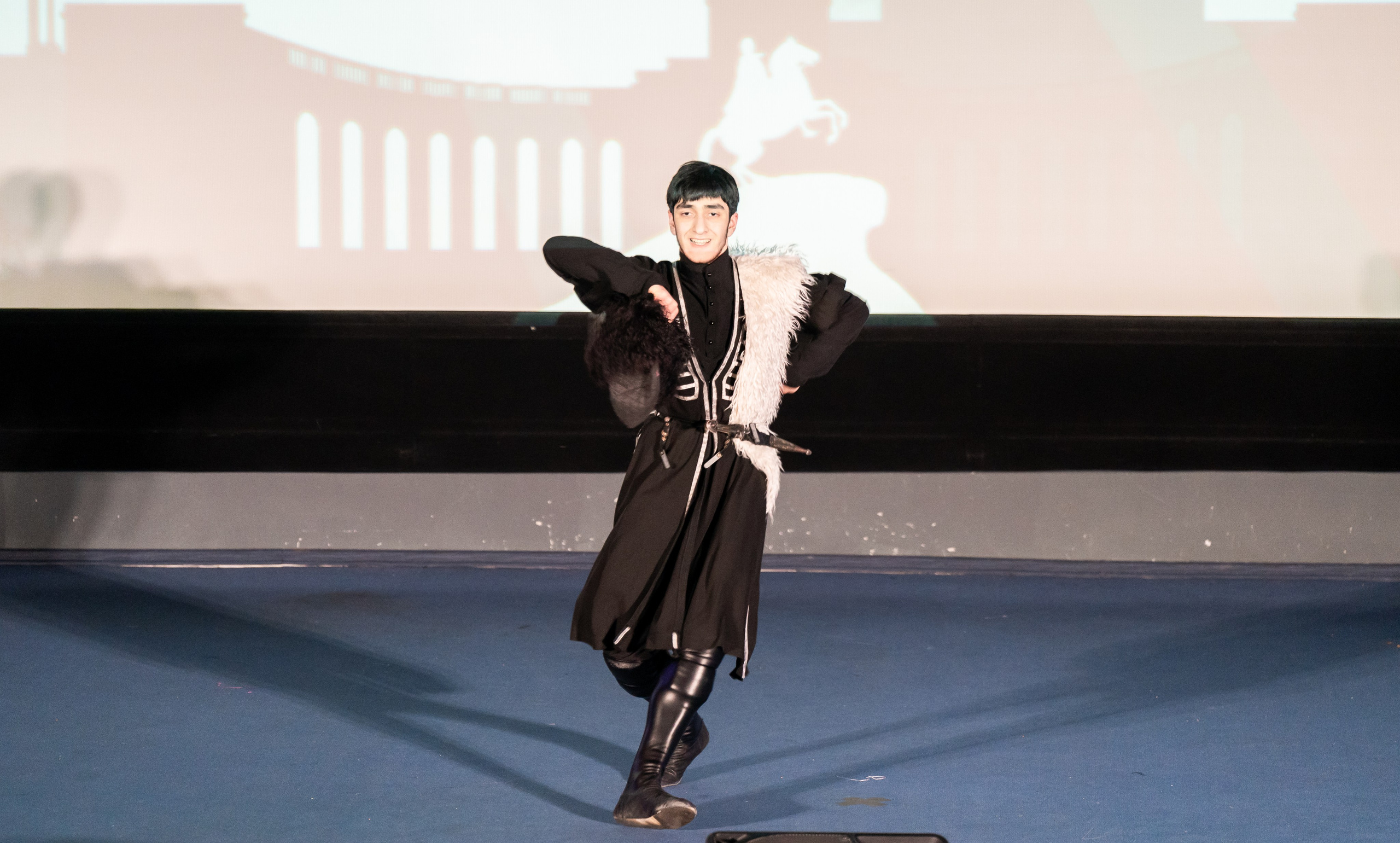 Молодой танцор в традиционном мужском костюме с папахой на сцене фольклорного фестиваля. Санкт-Петербург, 2026. Фото: Мальцев Евгений.