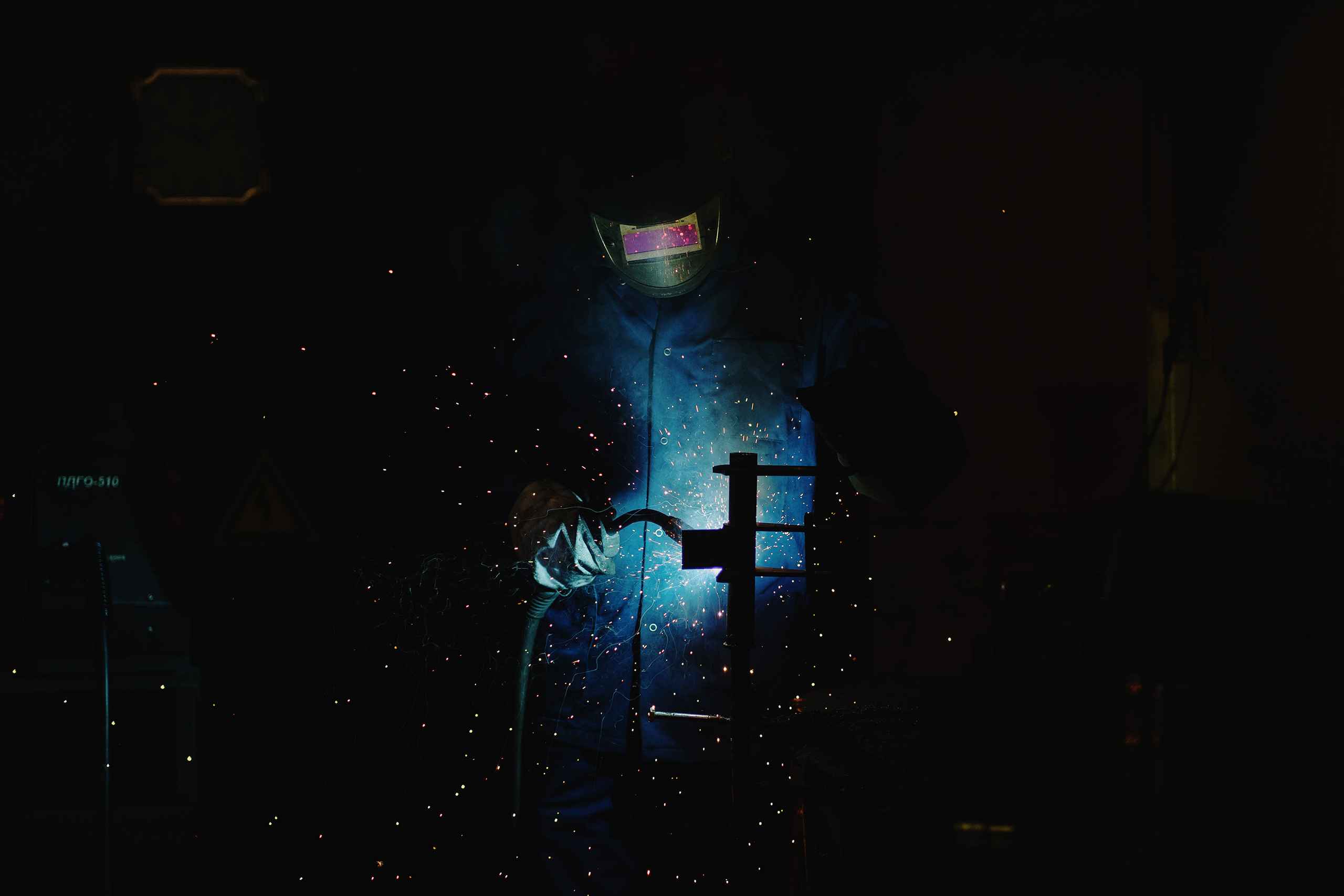 Сварщик в защитной маске, варит металл