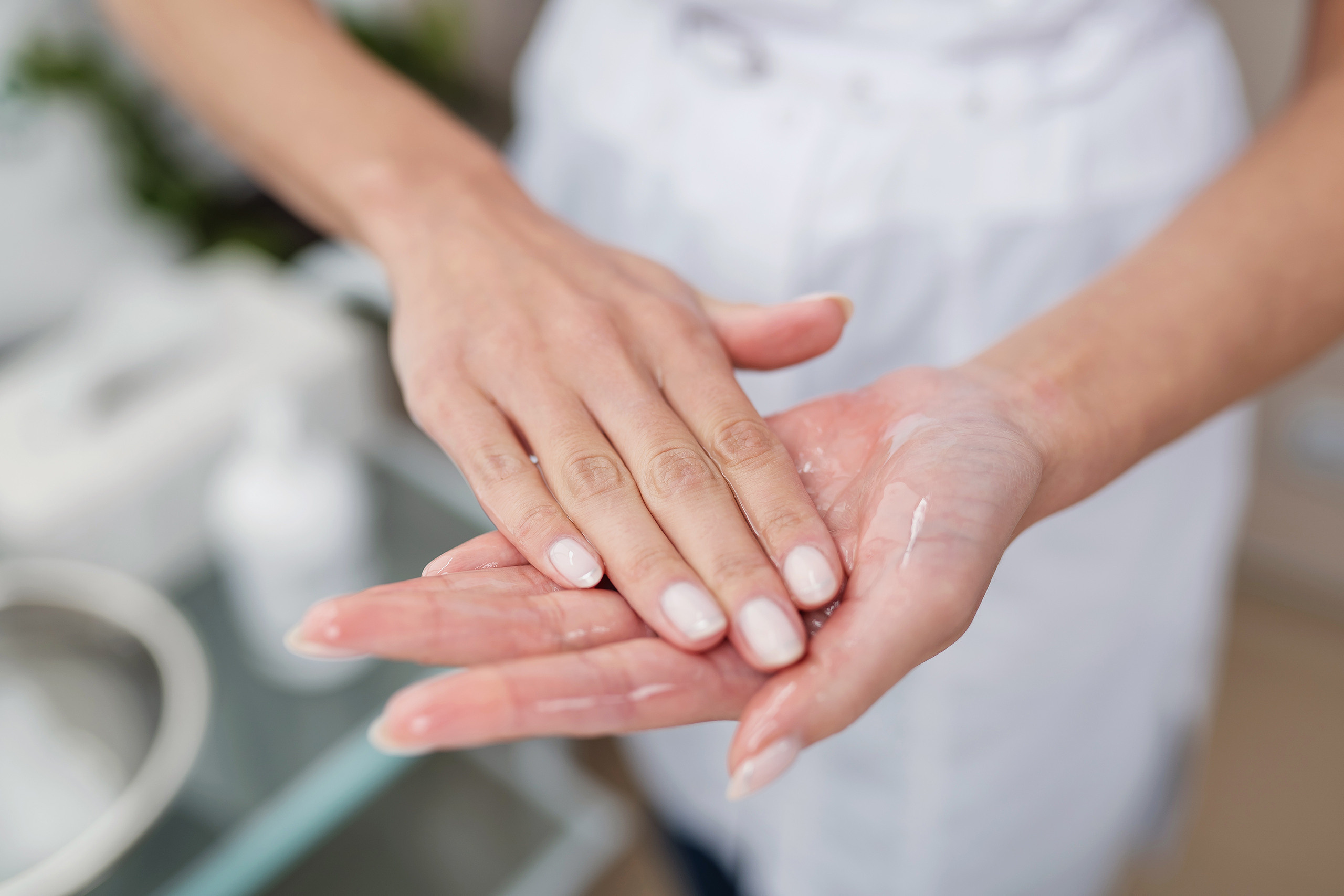 Девушка с ухоженными руками наносит лосьон