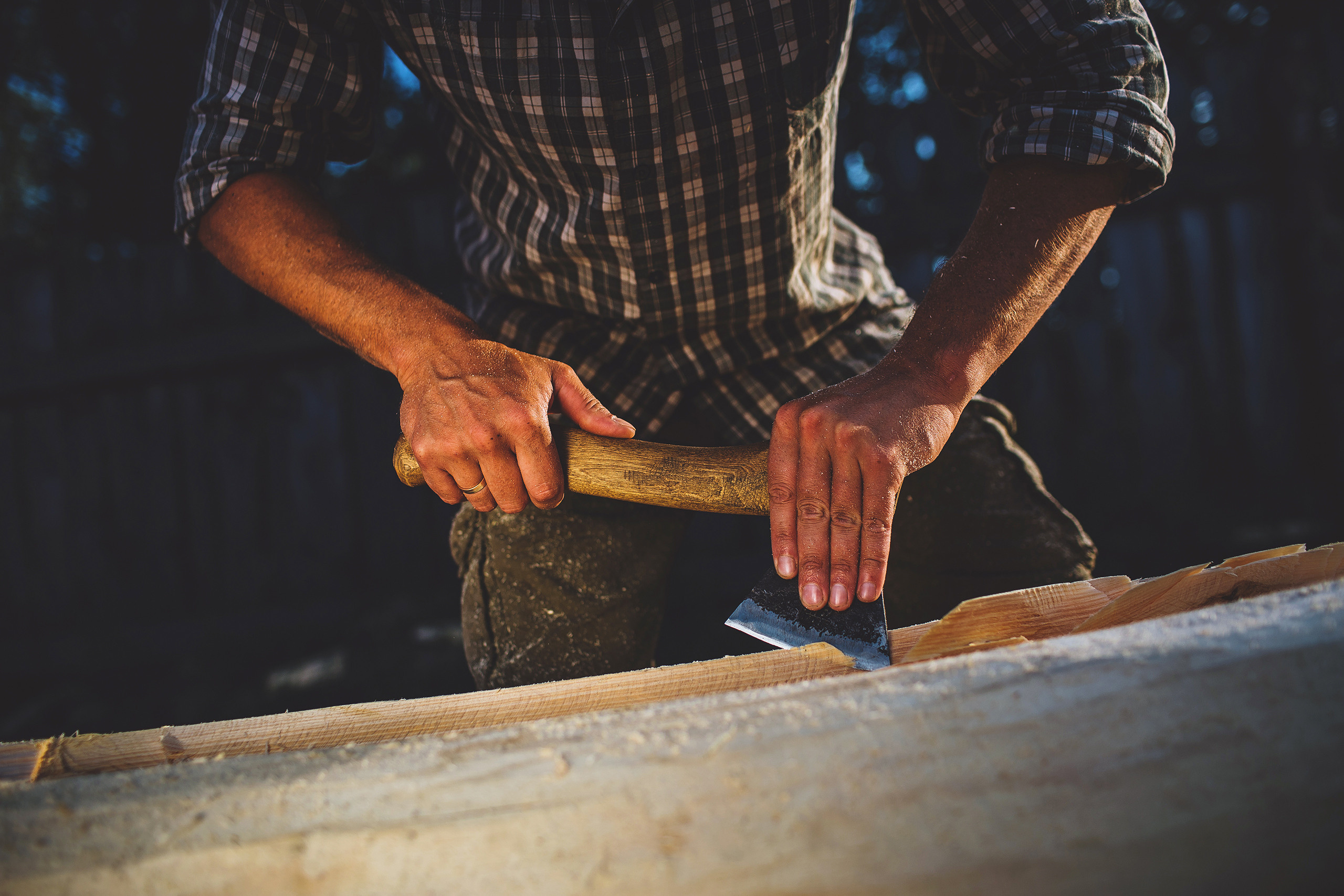 Строитель обрабатывает брус топором