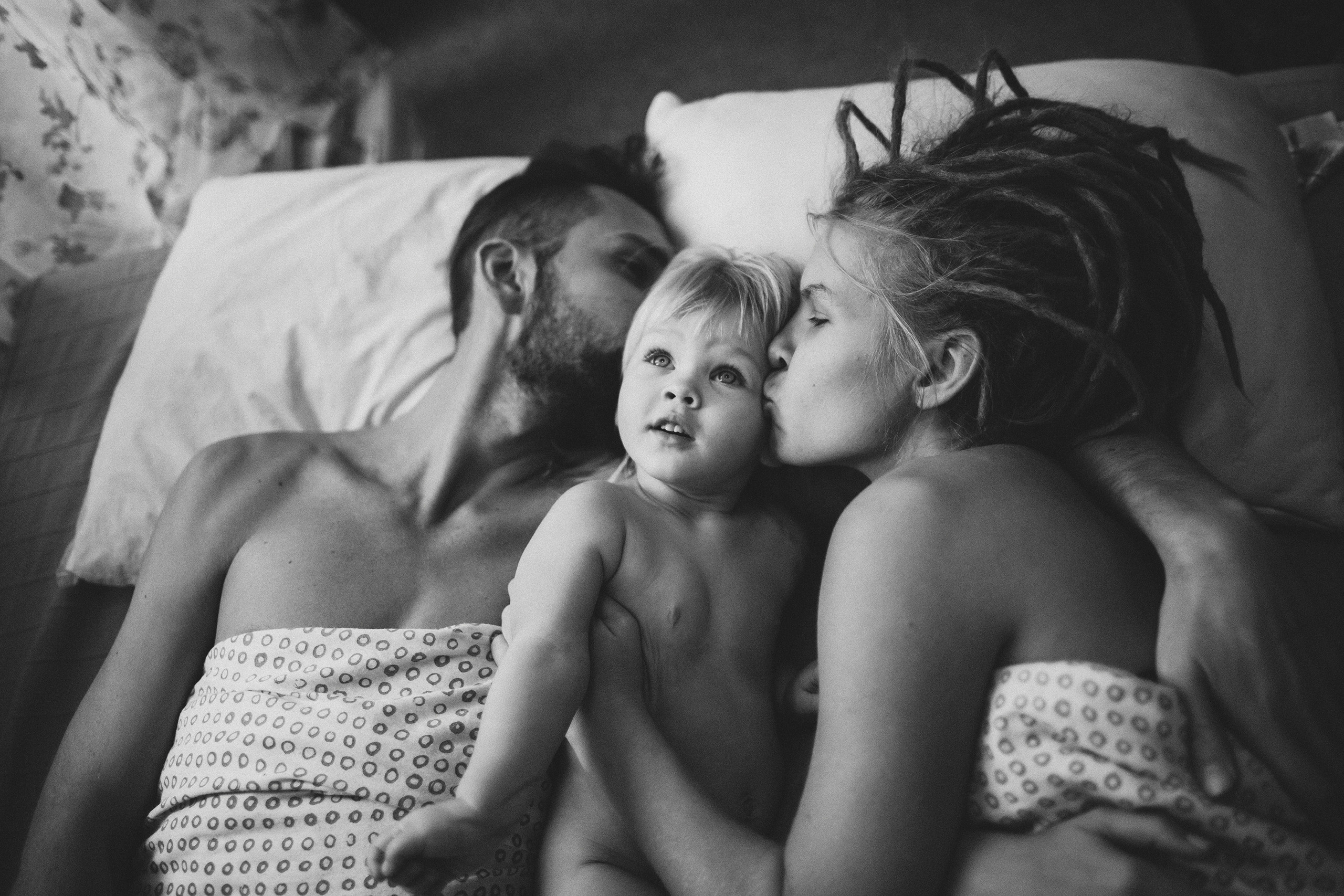 Родители играют с ребёнком в кровати