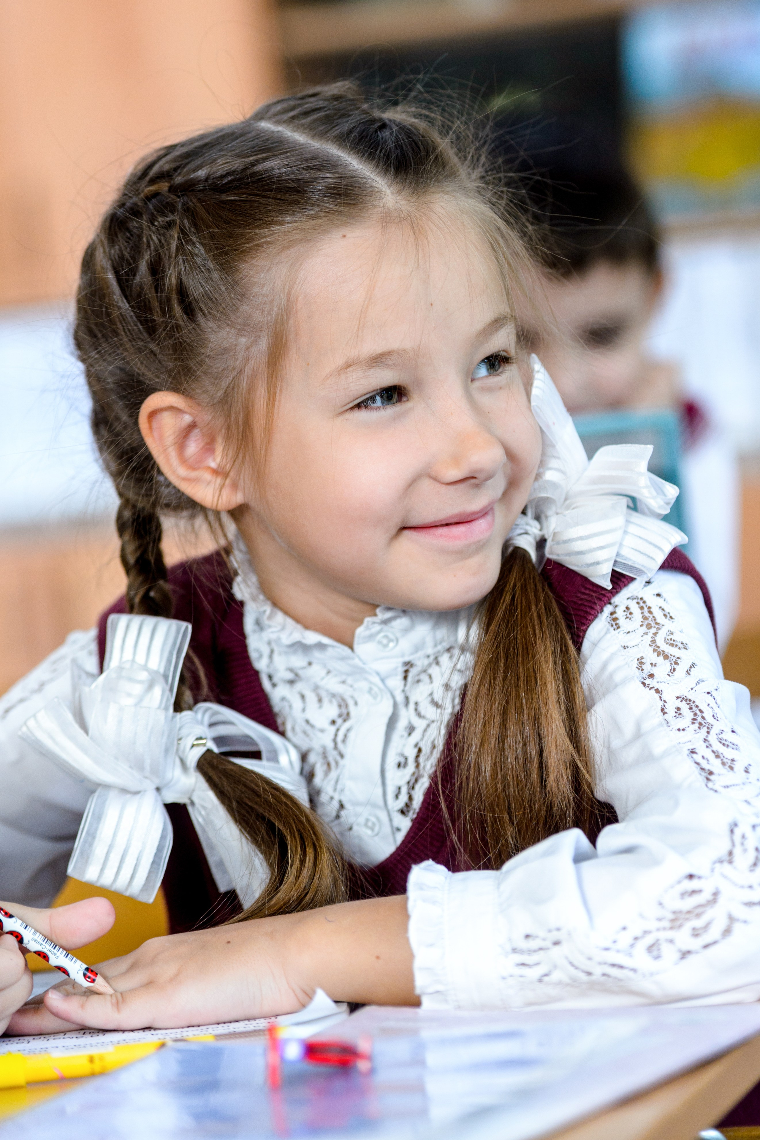 Улыбающаяся школьница с бантами на занятии в классе