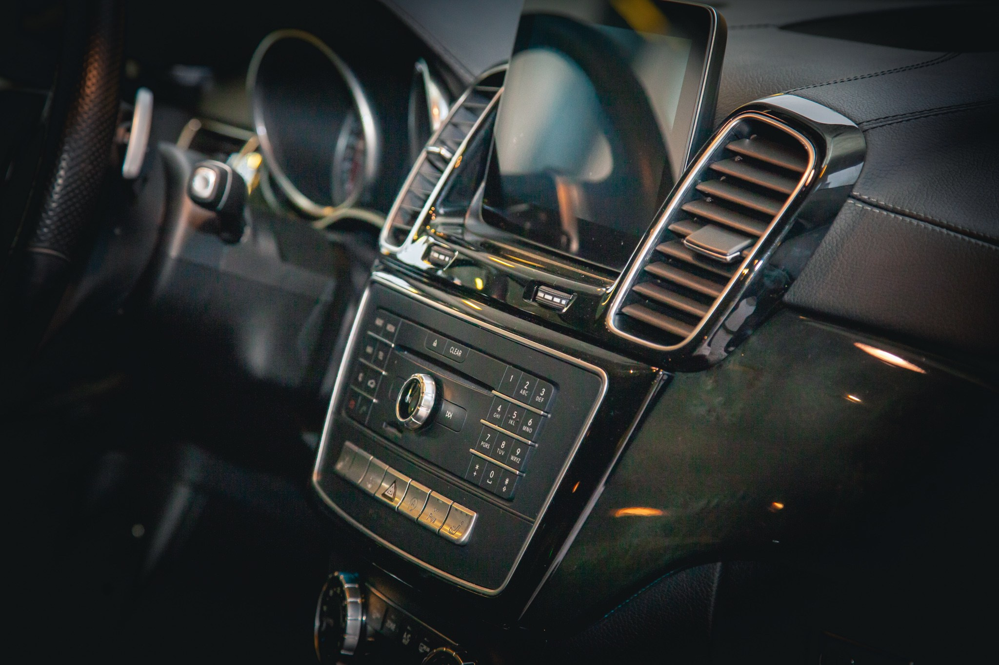 Детальный взгляд на центральную консоль Mercedes-Benz с дисплеем и кнопками управления. Высокотехнологичная система обеспечивает удобство водителя