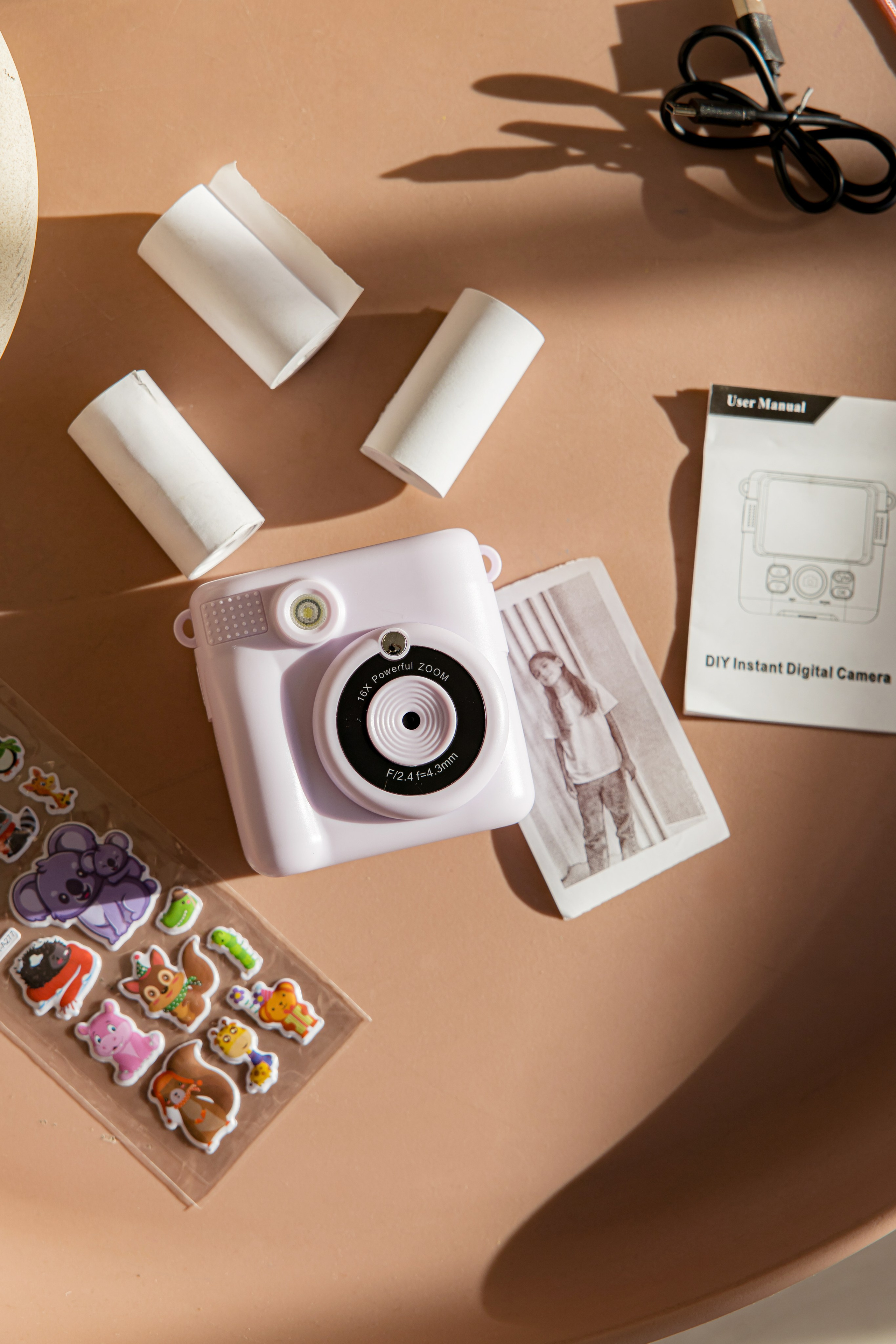 Розовый фотоаппарат моментальной печати лежит на столе на солнце