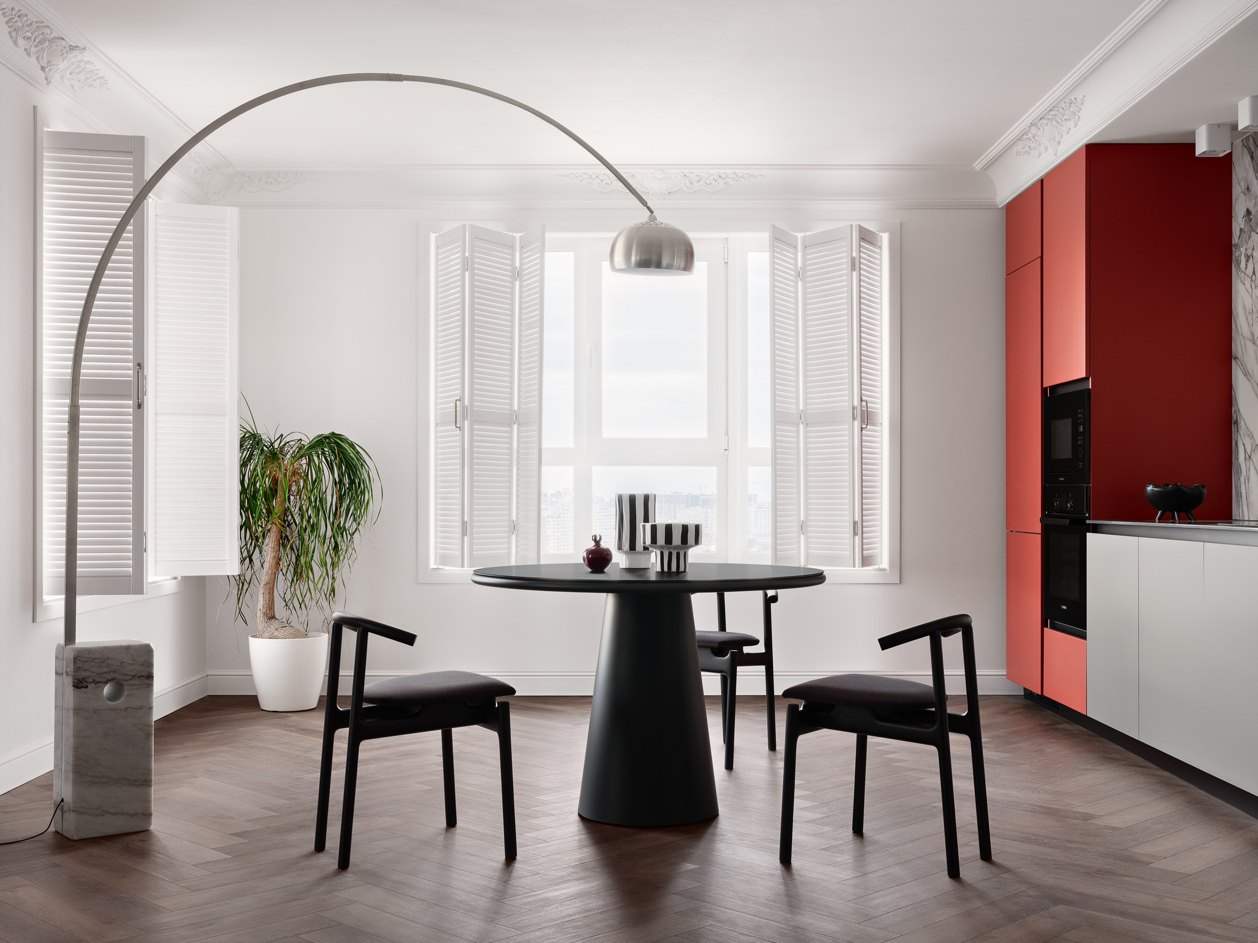 Обеденная зона с черным круглым столом, дизайнерскими стульями, арочным торшером и зелёным растением в белом кашпо. Интерьер создан дизайнером Антоном Логиновым, стилизован Алёной Мощенской, фото Сергея Денисенко.