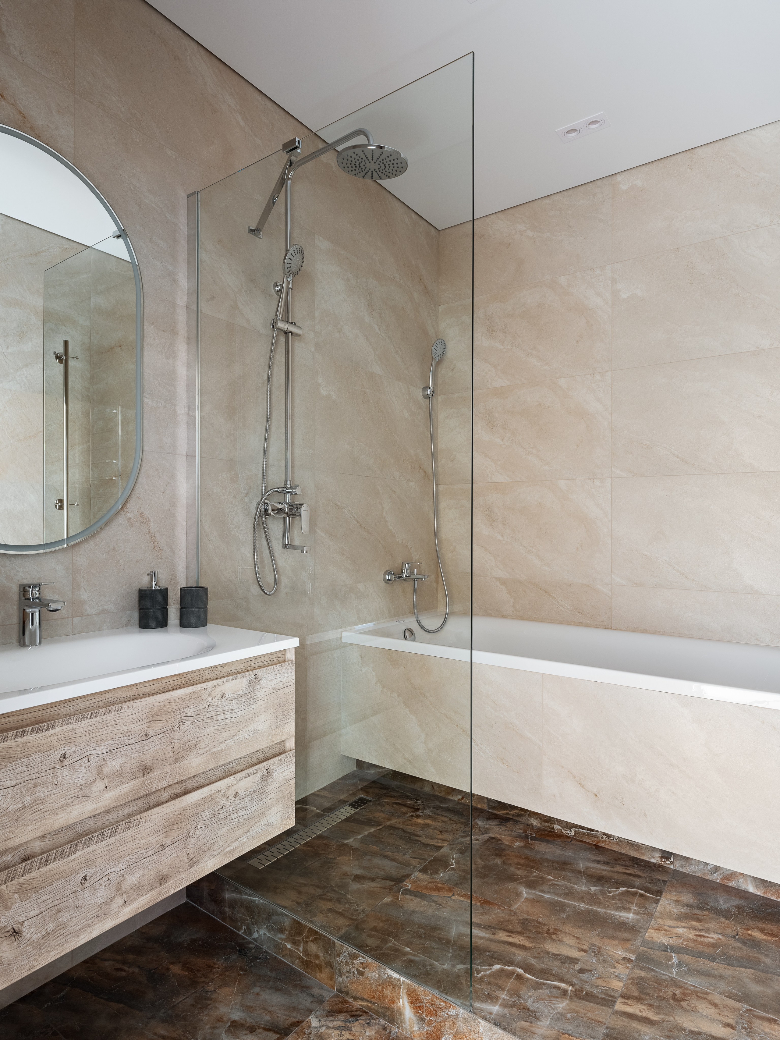 Современная ванная комната с душевой зоной за стеклянной перегородкой, ванной и плиткой под камень, сочетающейся с деревянной тумбой под раковину. Дизайн Наталья Бунеева, стилист Наталья Якушева, фотограф Сергей Денисенко.