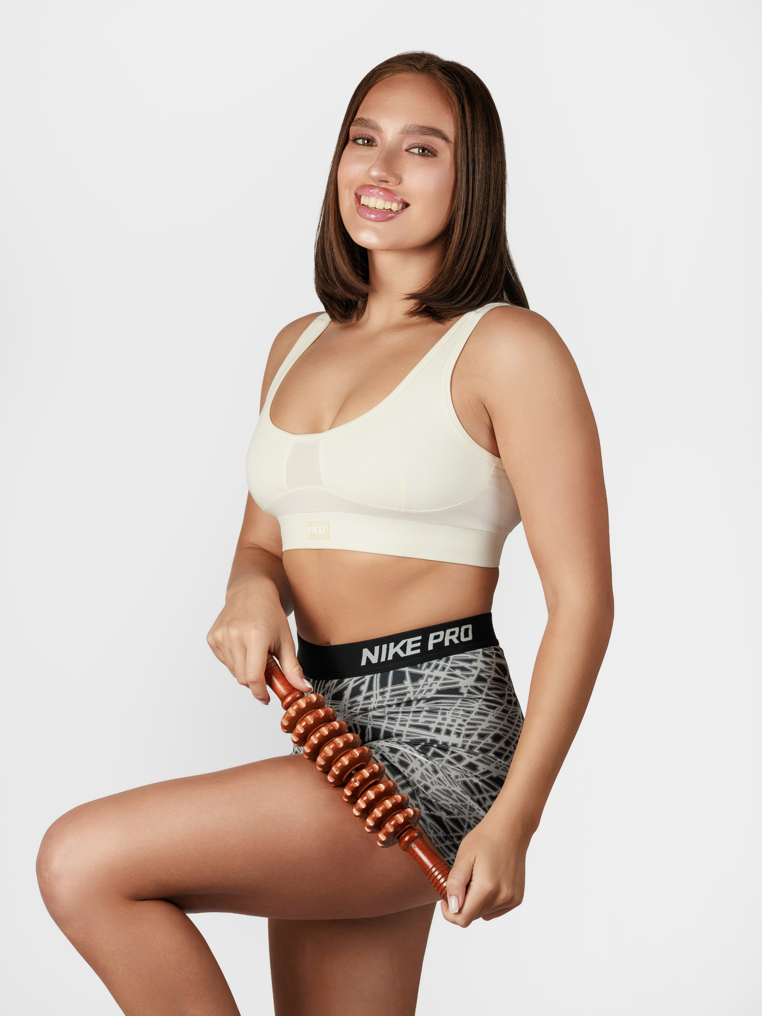 деревянный антицеллюлитный массажер у красивой девушки в руках на белом фоне