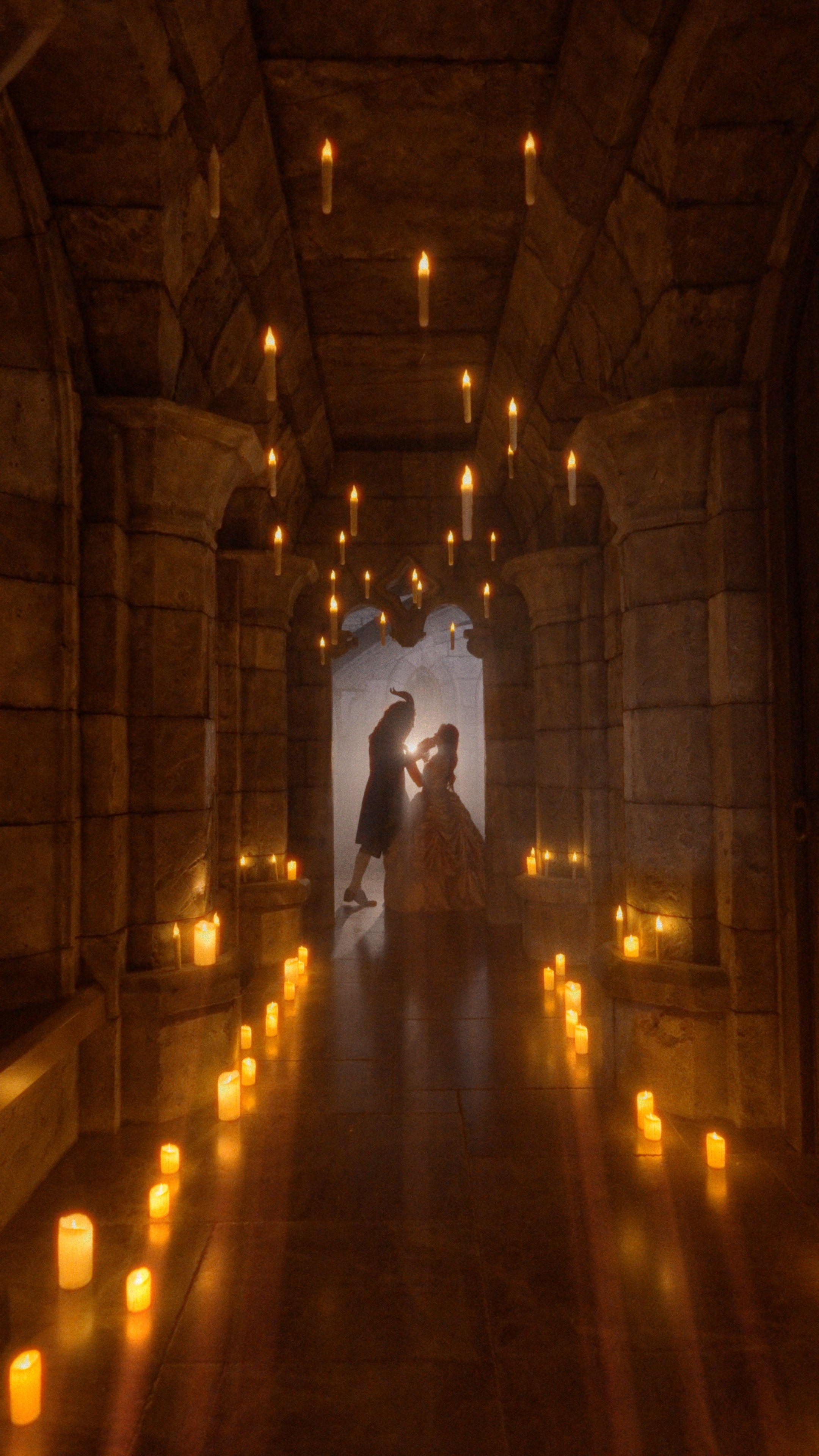 Силуэт пары в романтическом объятии среди свечей в тёмном коридоре замка Гарибальди, навевающий ассоциации с историей «Красавицы и Чудовища».