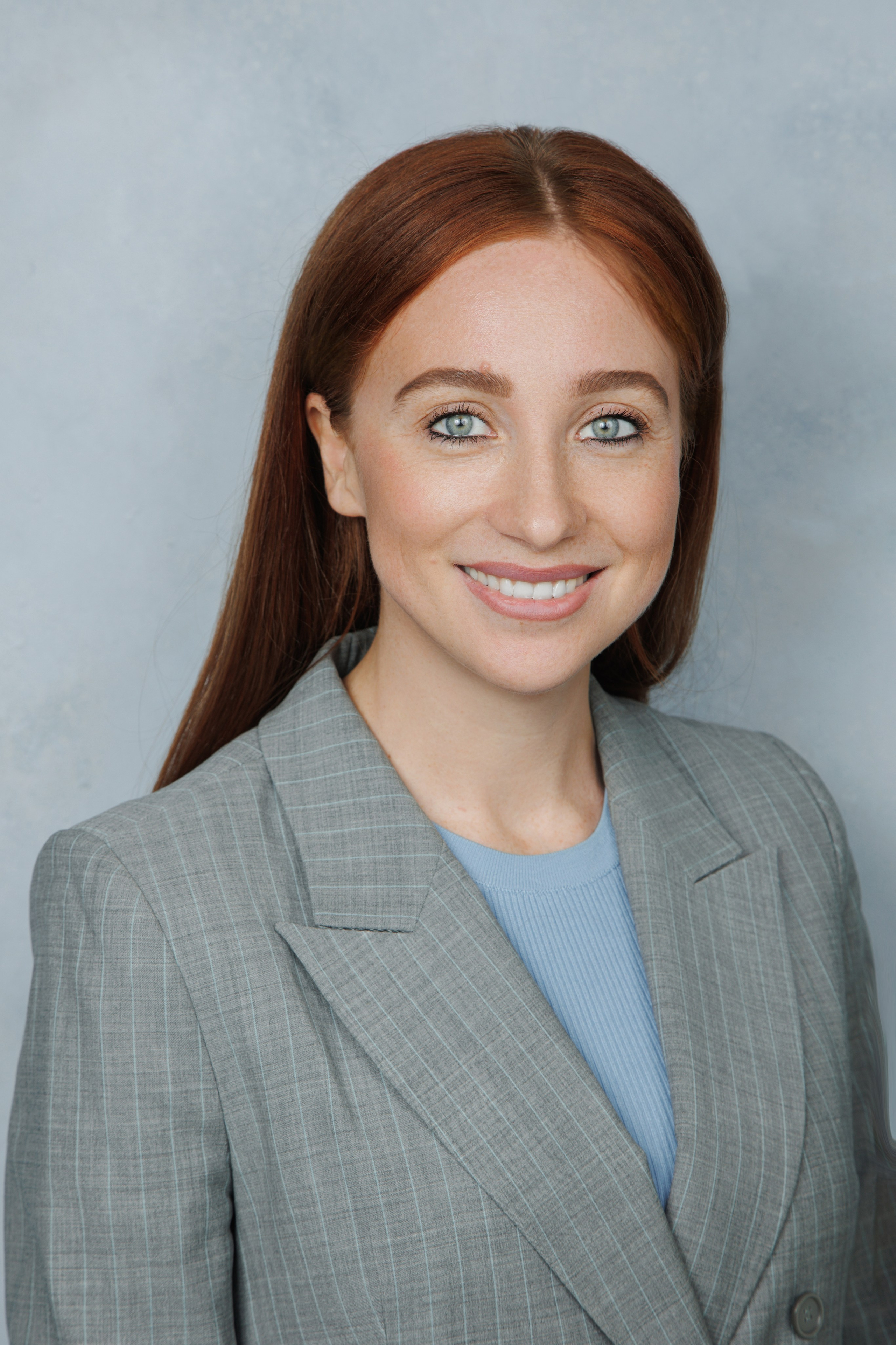 Улыбающаяся девушка в деловом стиле на спокойном голубом фоне.