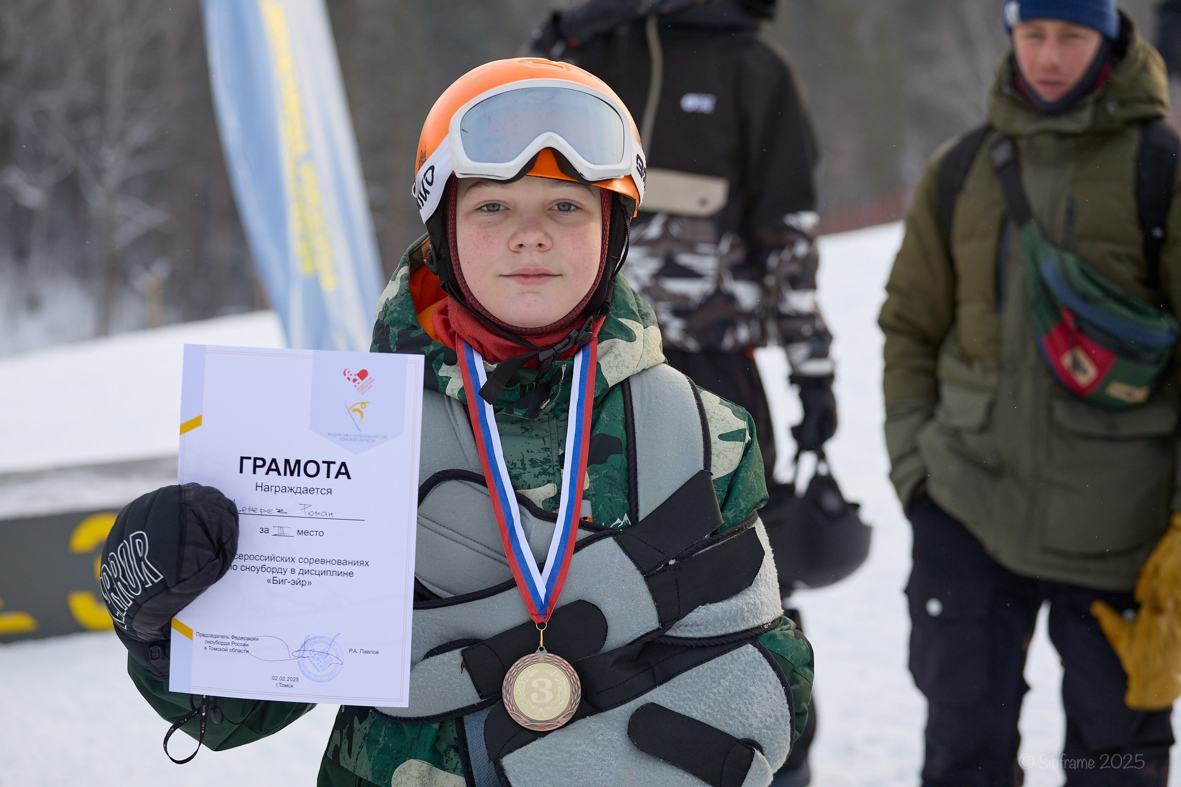 Юный сноубордист с травмой руки демонстрирует сертификат за второе место