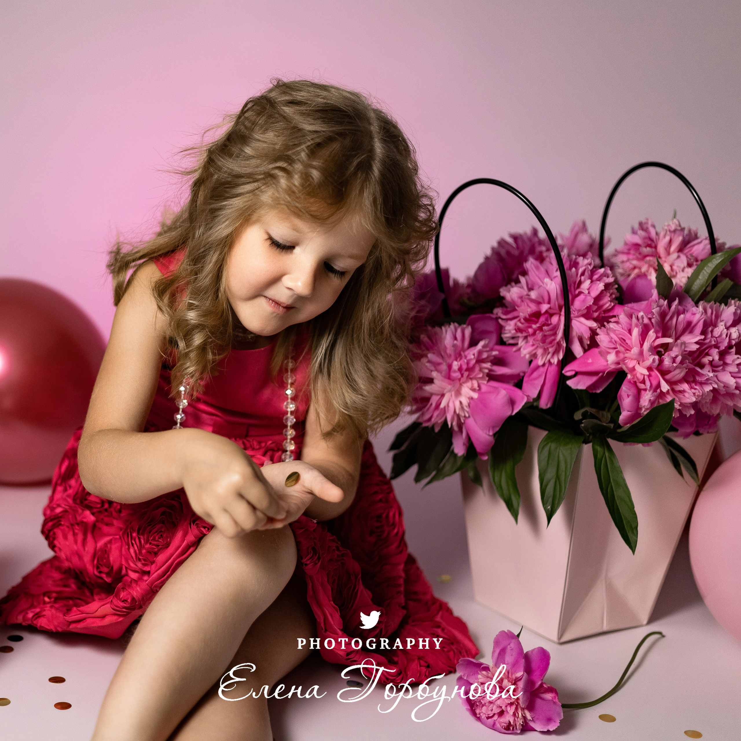 девочка модница в розовом с пионами раздувает блестки на фотосессии в студии