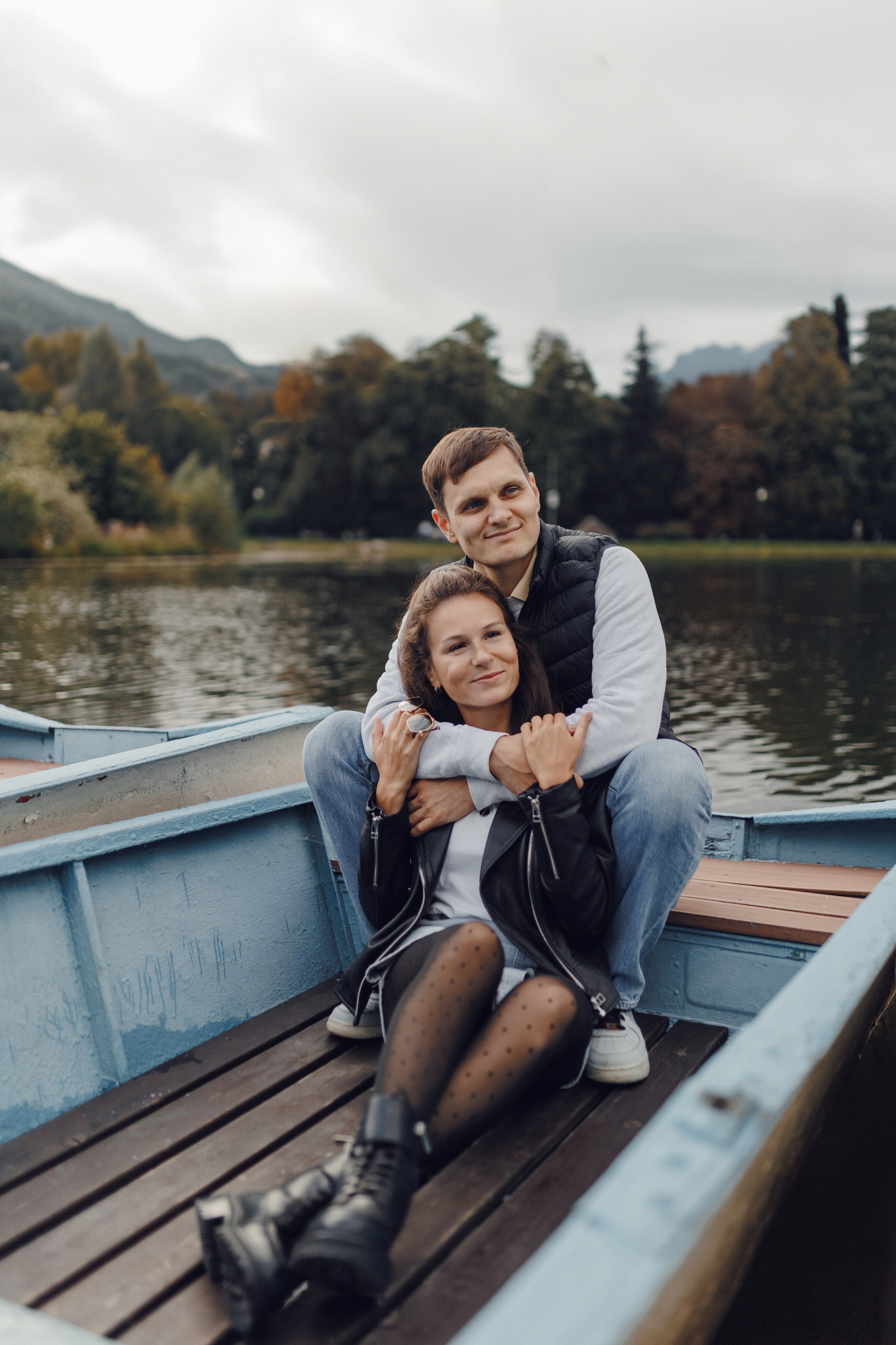 Сцена из фотосессии: муж и жена сидят в лодке на берегу озера на закате. Спокойствие и гармония на природе.