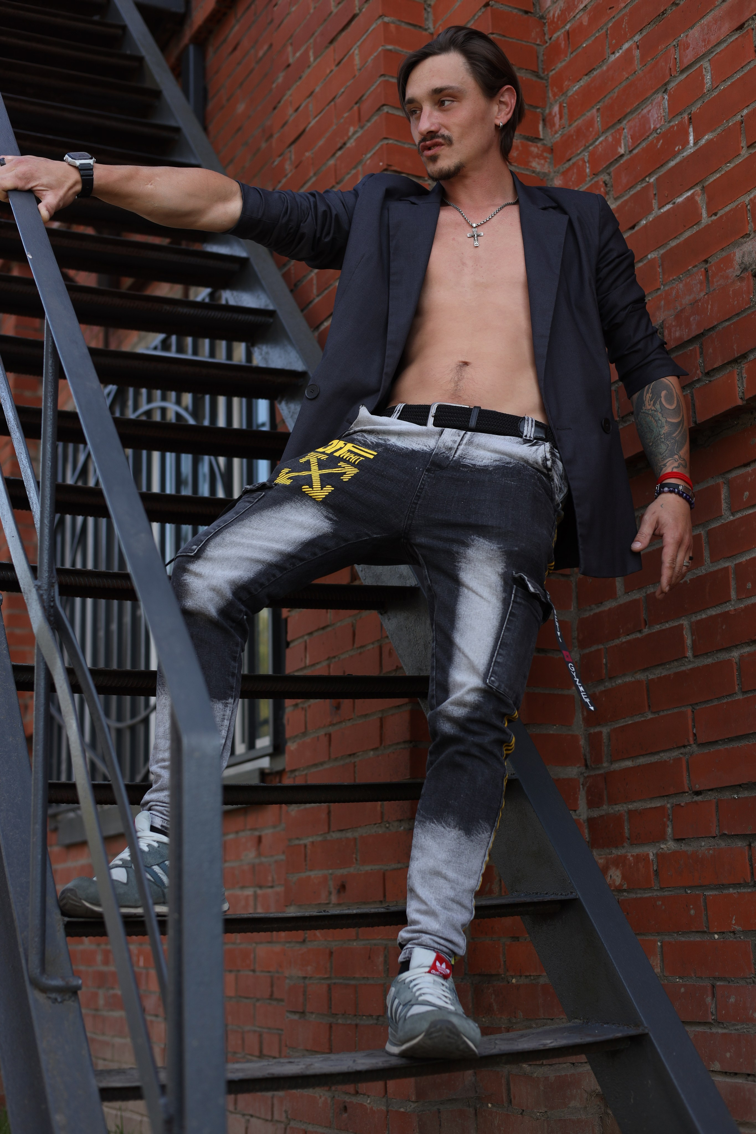 фотосессия для мужчин в джинсах пиджаке и с голым торсом стоит на лестнице