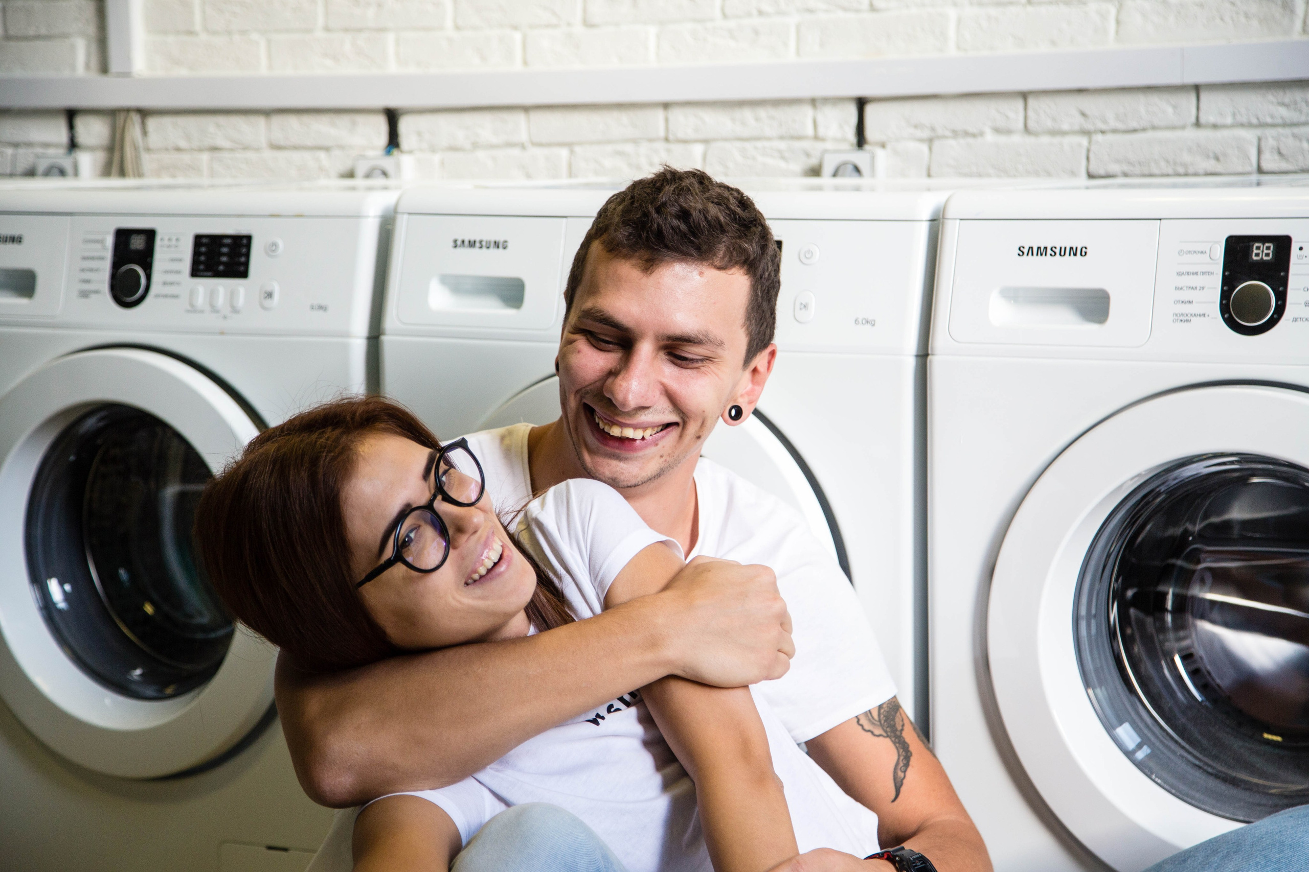Фотокадр обнимающих парня и девушки возле стиральных машин