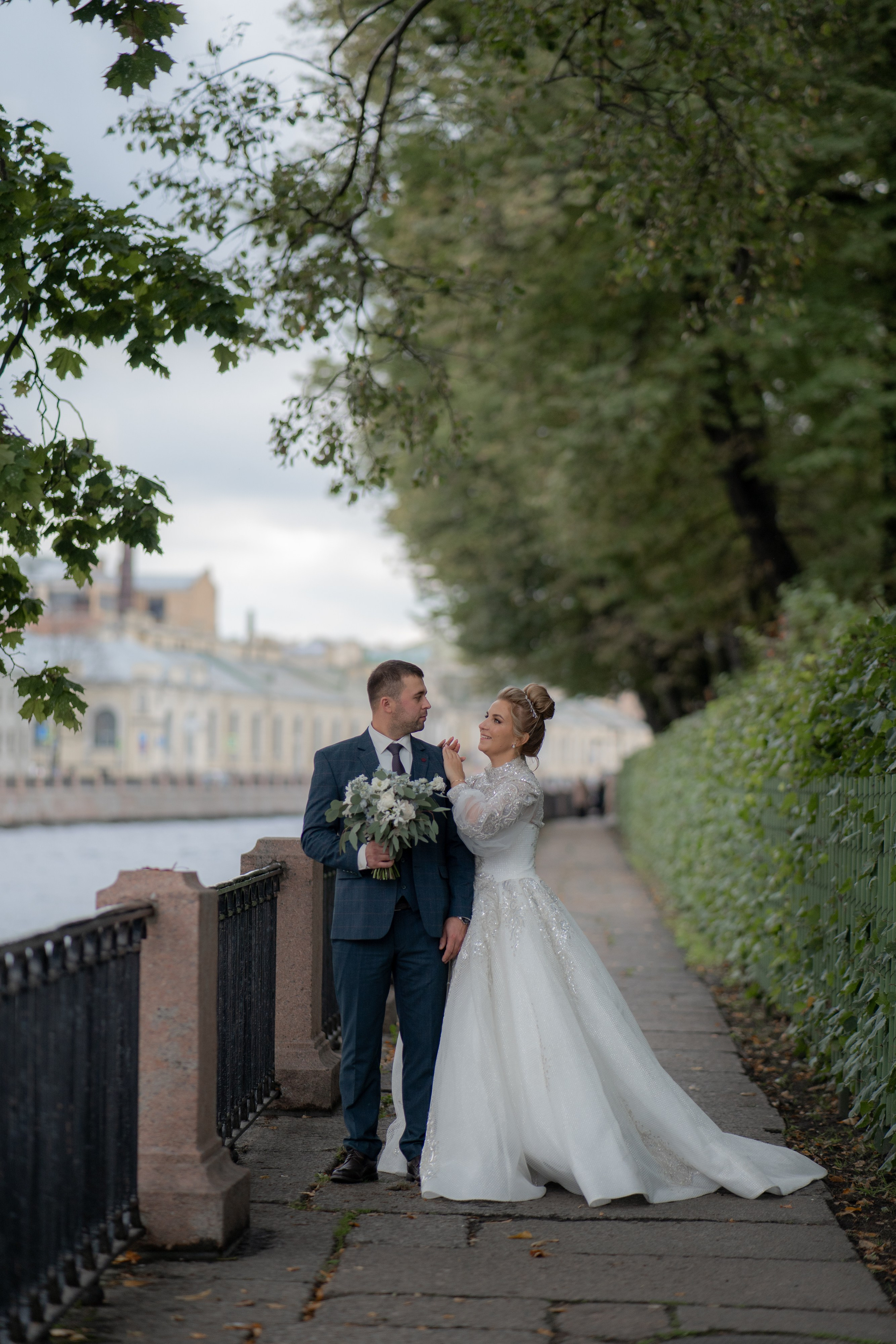 жених и невеста идут по набережной вдоль летнего сада