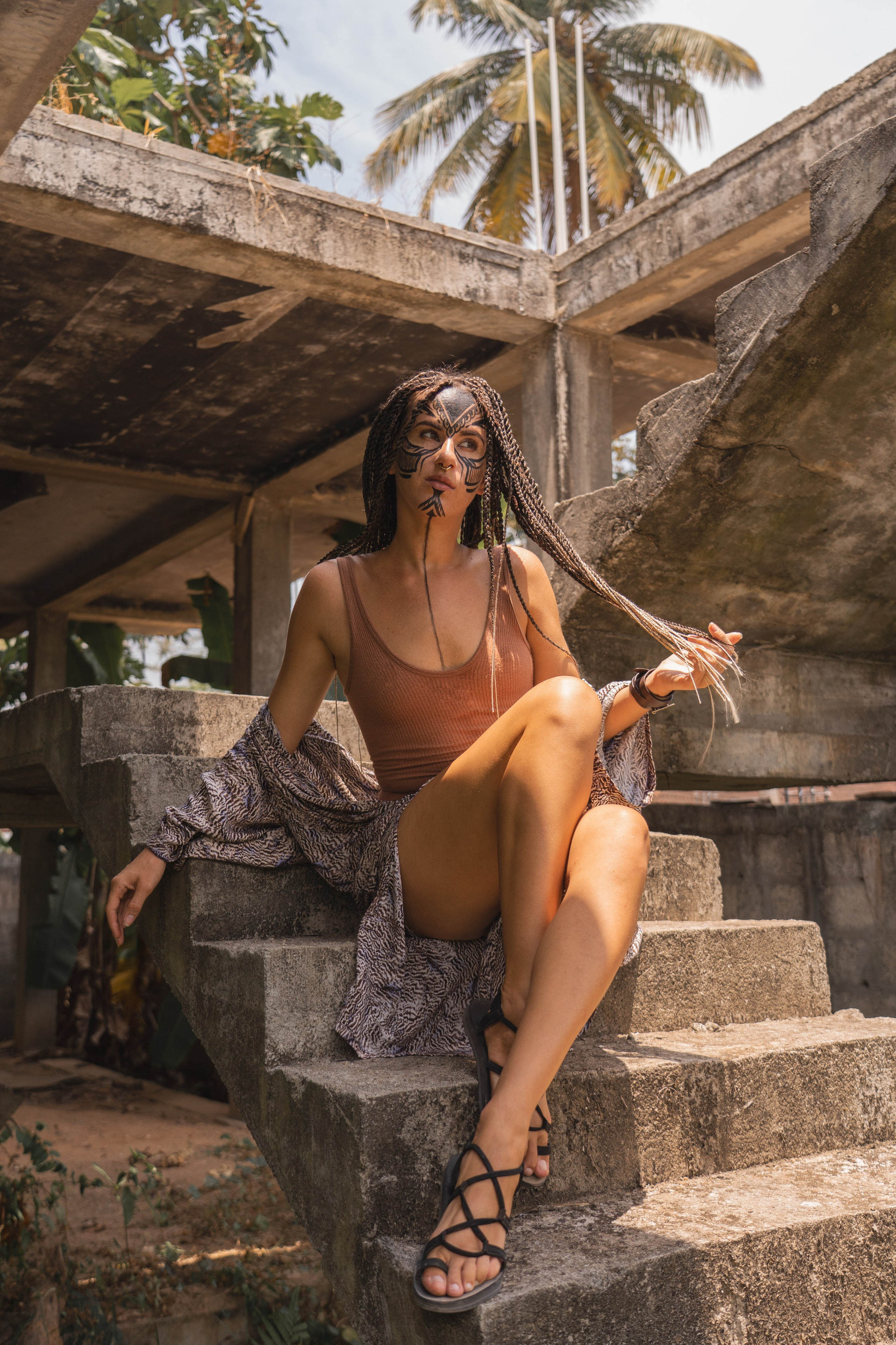 a girl with braids and face paint against vines and tropical plants