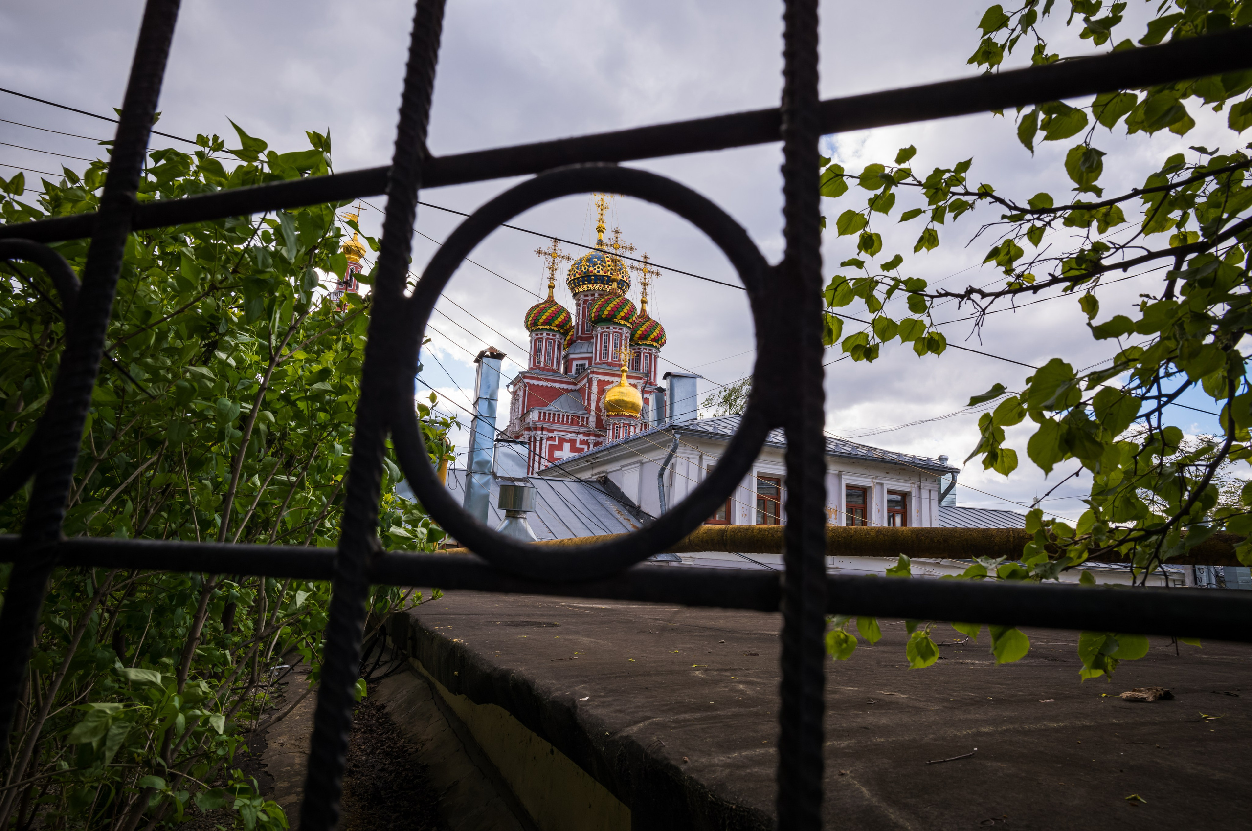 Вид на церковные купола через круглое видовое отверстие в ограде в Нижнем Новгороде