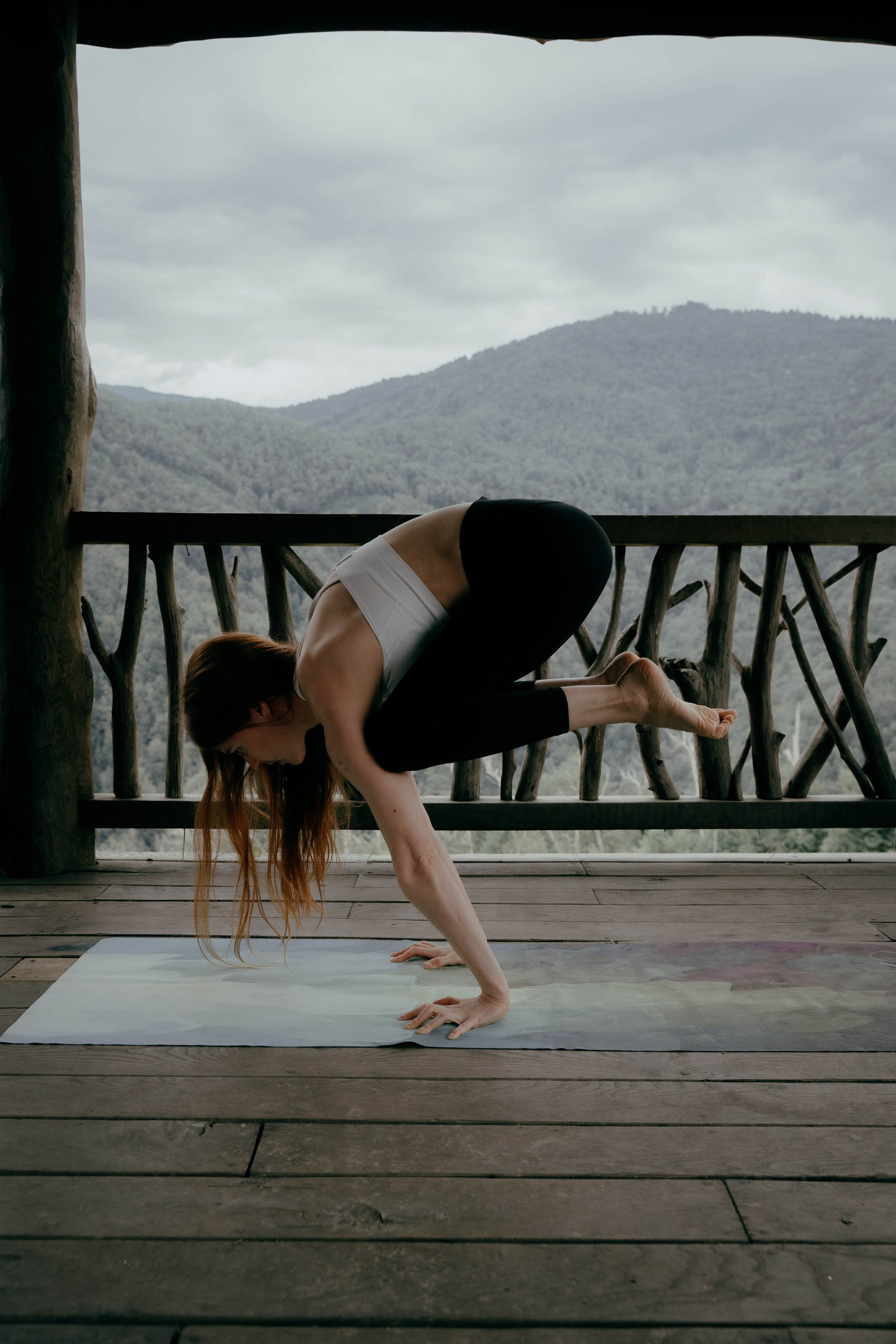 Девушка стоит на стойке на руках в беседке 