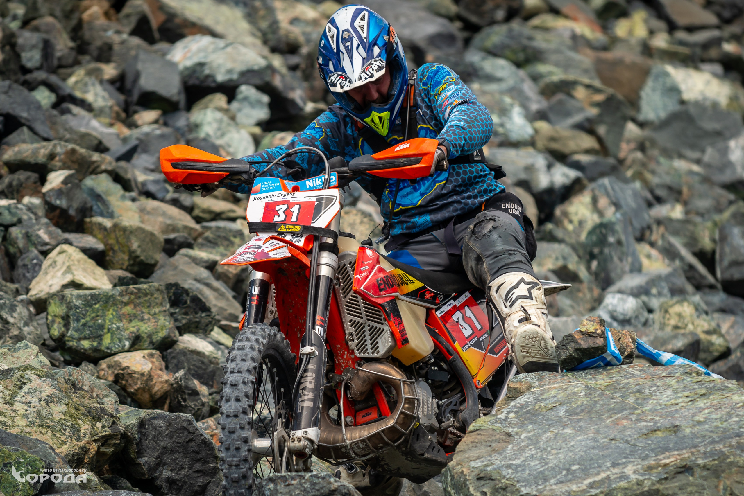 Гонщик на эндуро маневрирует между крупными камнями, номер 31 на обтекателе.