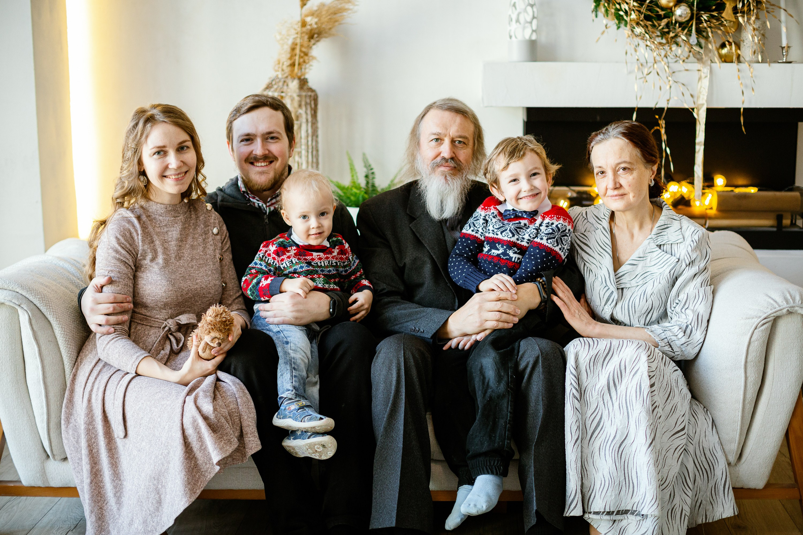 Новогодняя фотосессия в фотостудии. На диване сидит три поколения. Дедушка, бабушка, папа, мама и их дети, внуки.
