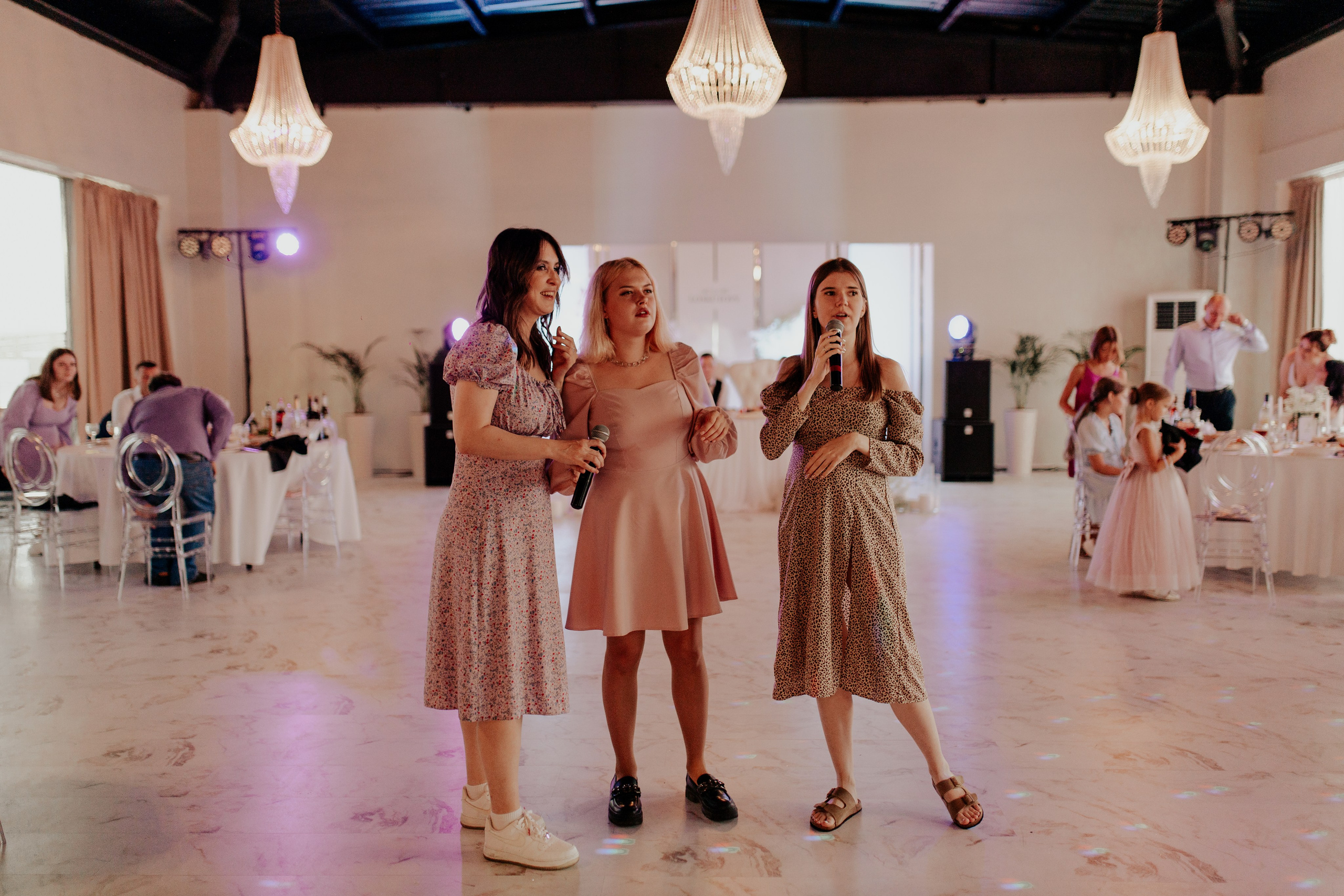 Подружки невесты внимательно слушают речь в тёплой атмосфере праздника — романтика вечера