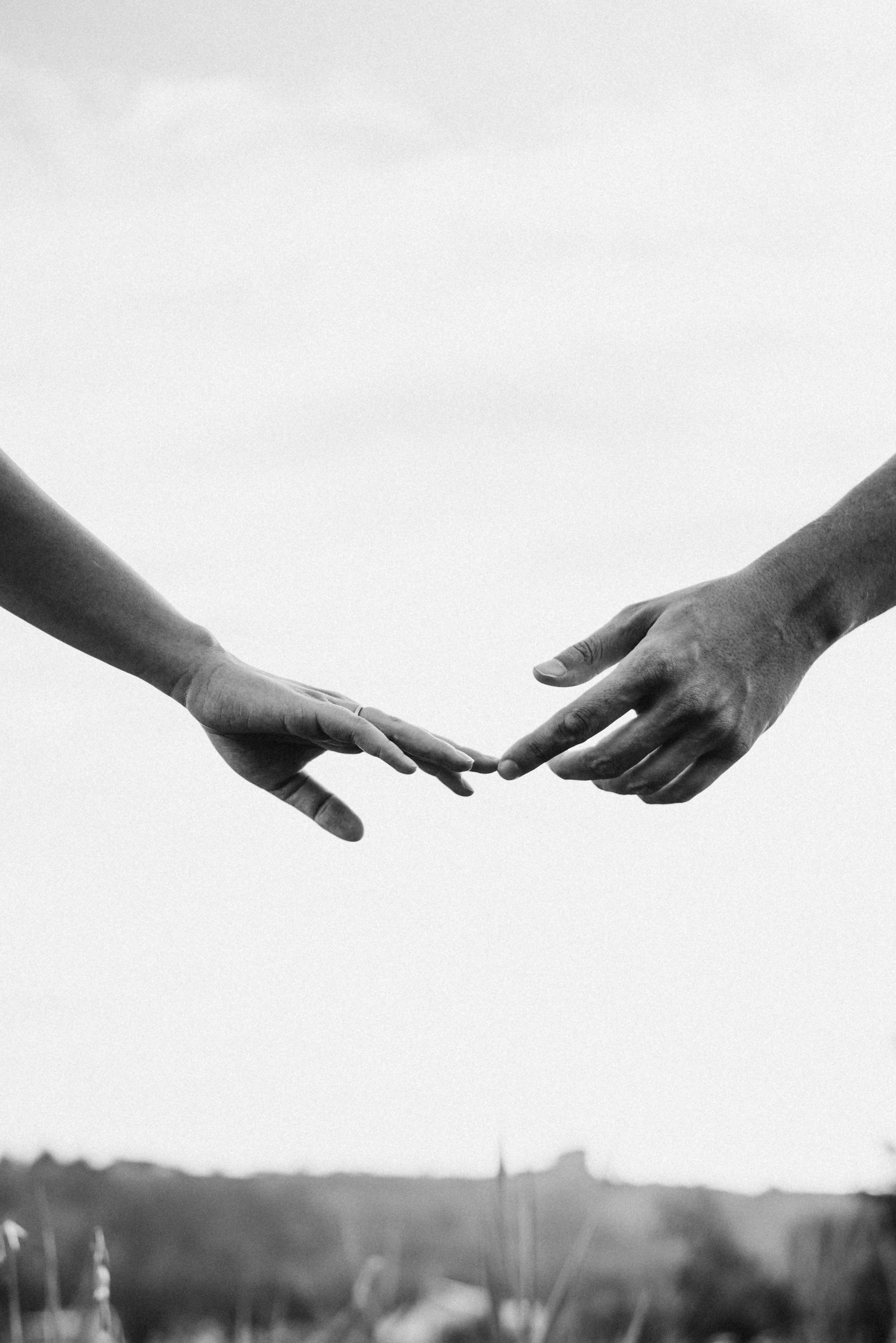 Черно-белая фотография двух рук, нежно касающихся пальцами друг к другу