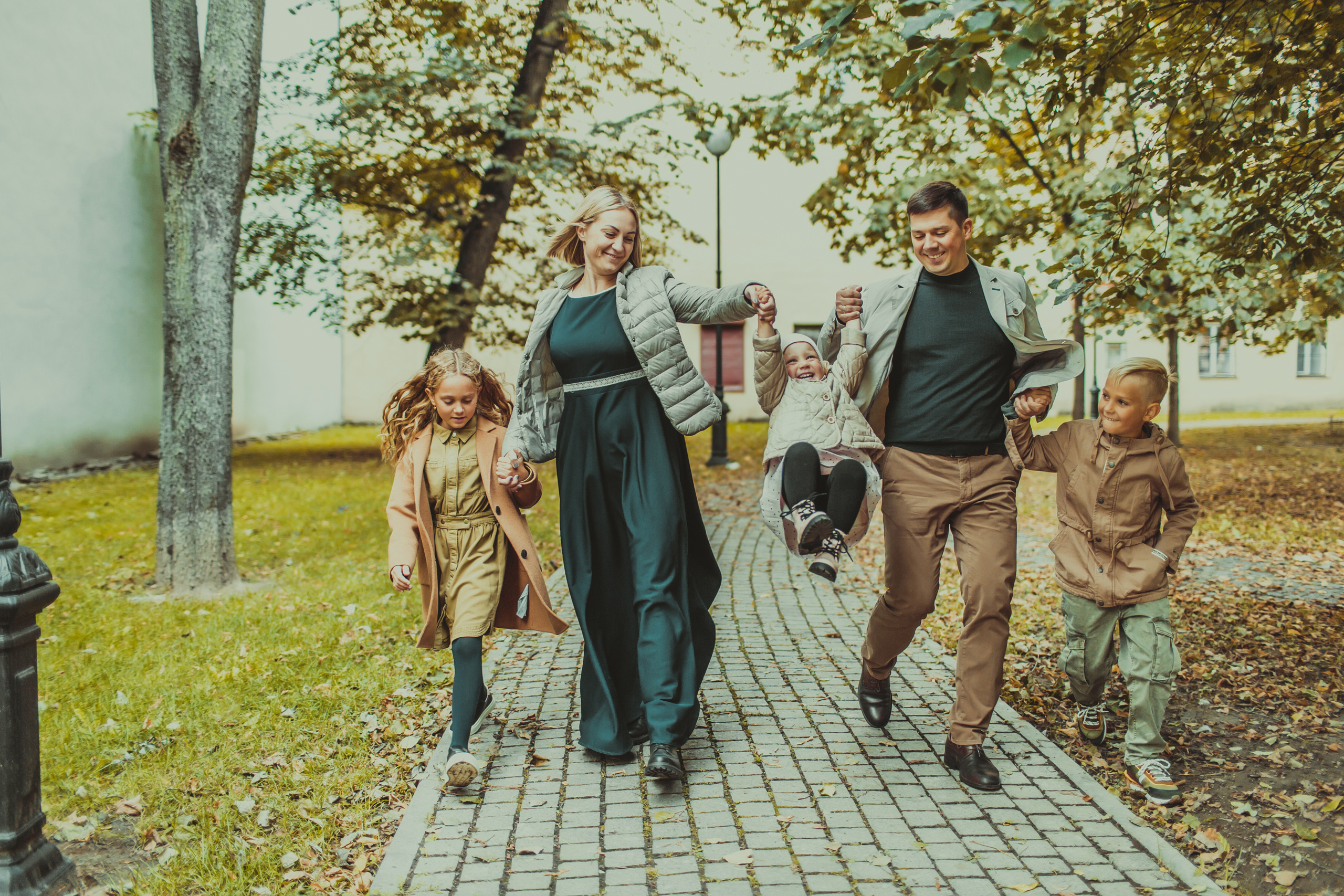 родители с тремя детьми гуляют по дорожке в сквере на Петроградской