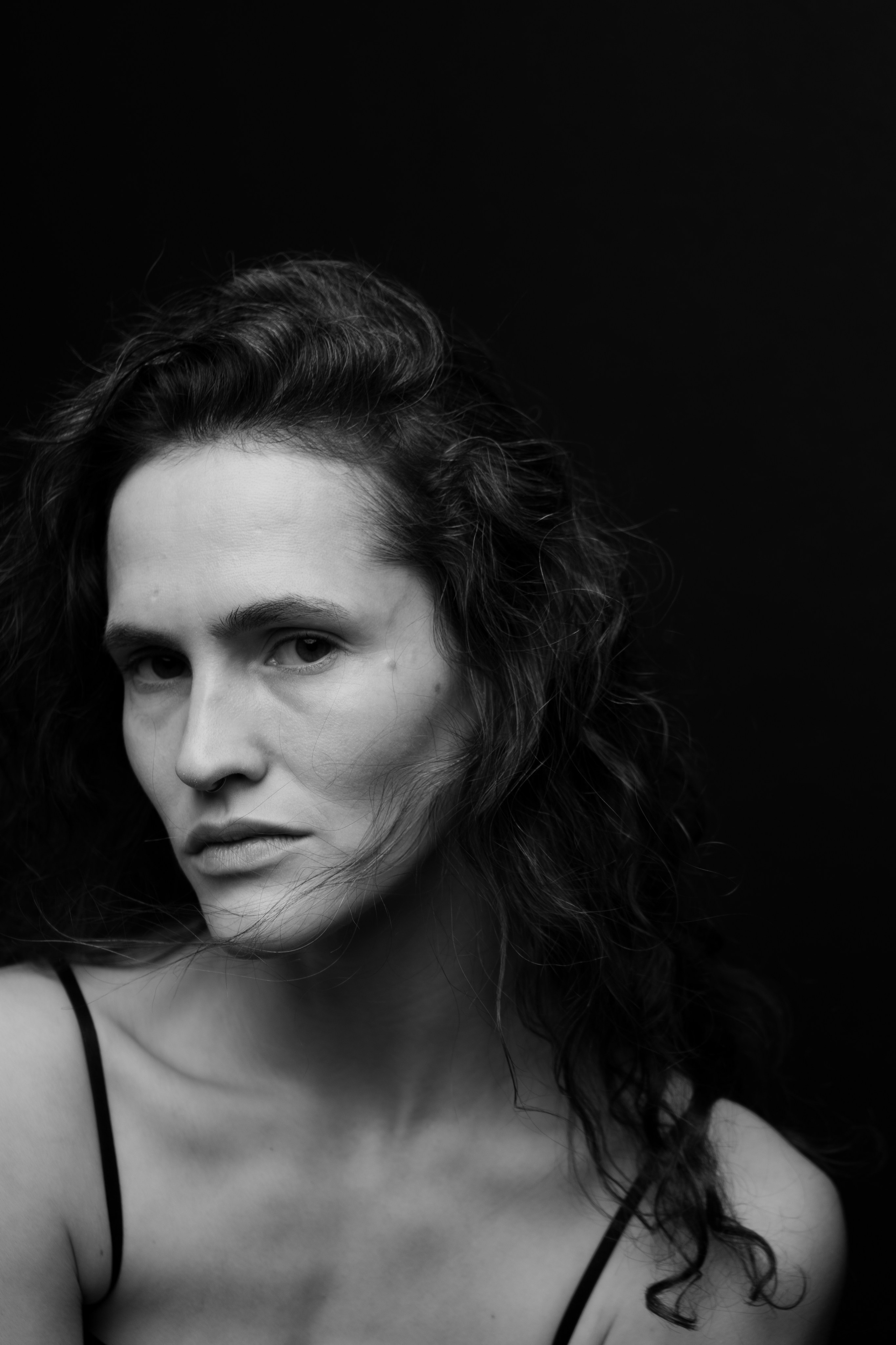 Девушка позирует на чёрном фоне и смотрит нахмурившись