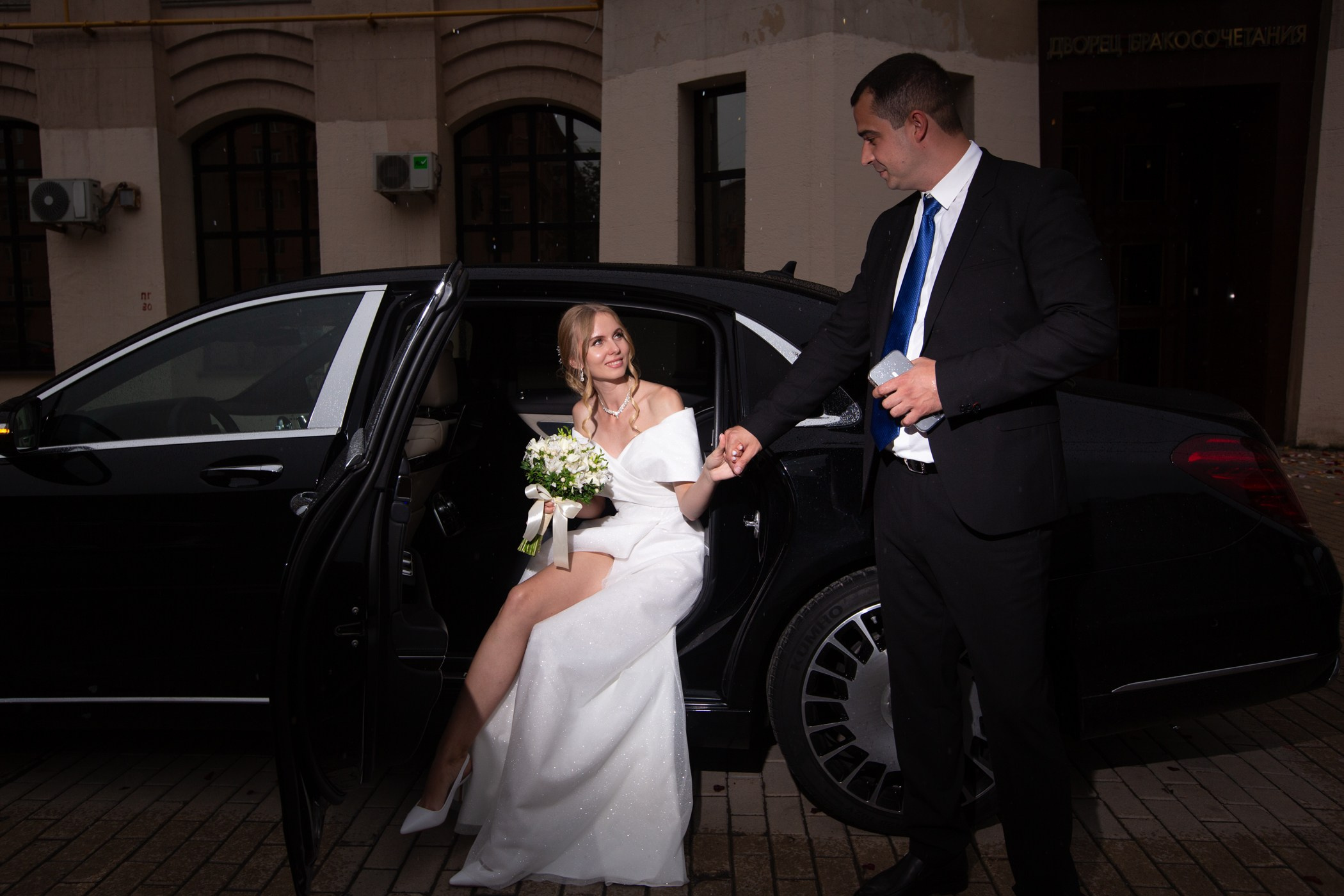 свадебная фотосессия где жених дает руку невесте чтобы она вышла из машины 