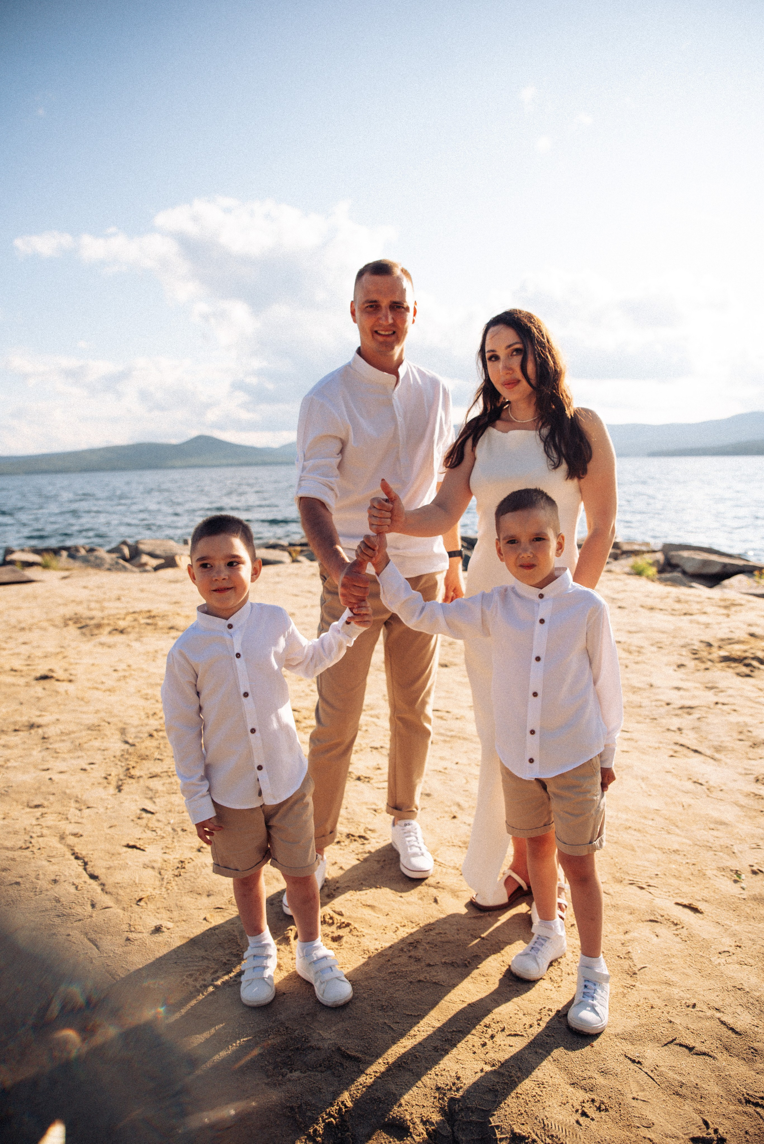 Семейная прогулка летом на берегу озера по пляжу