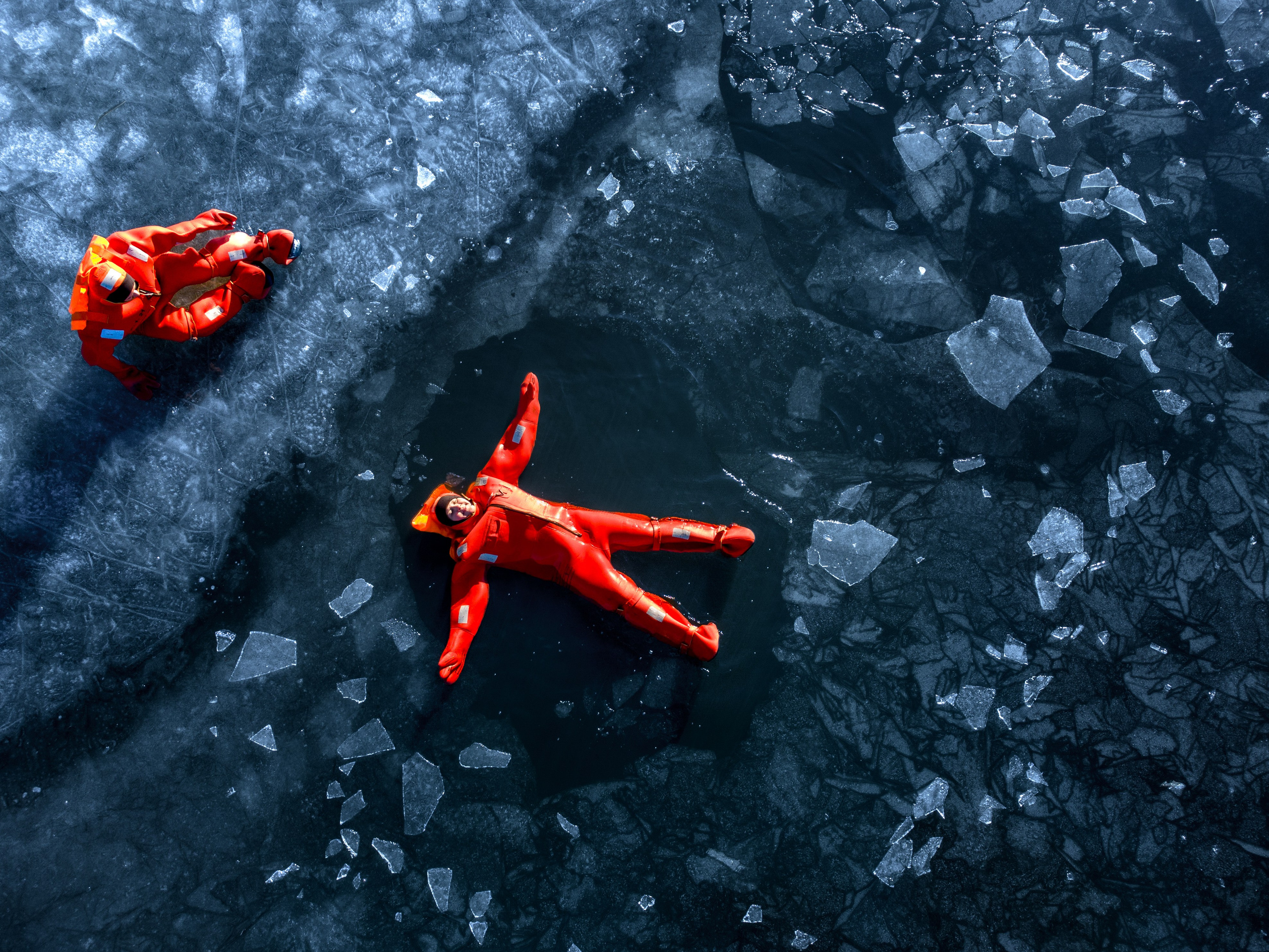 Люди купаются среди льдин, в спасательных оранжевых термо костюмах, айс флоатинг Ярославль