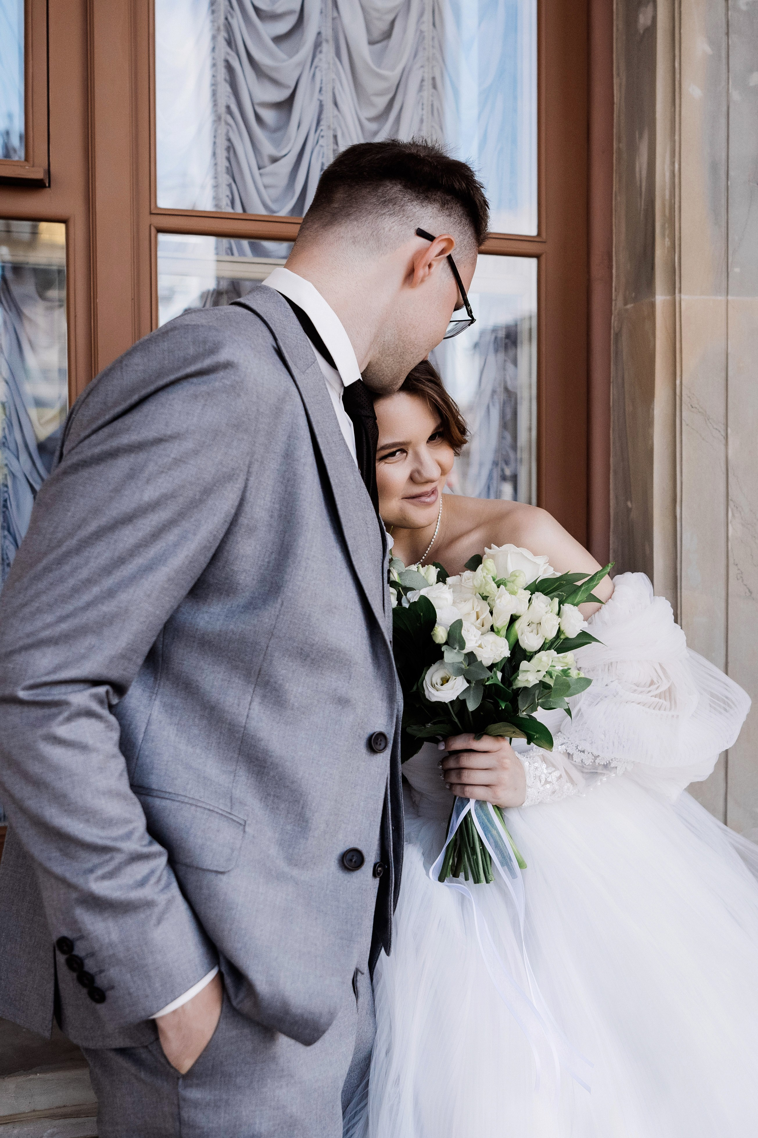 Жених и невеста у деревянного окна — тёплый портрет на фоне фасада
