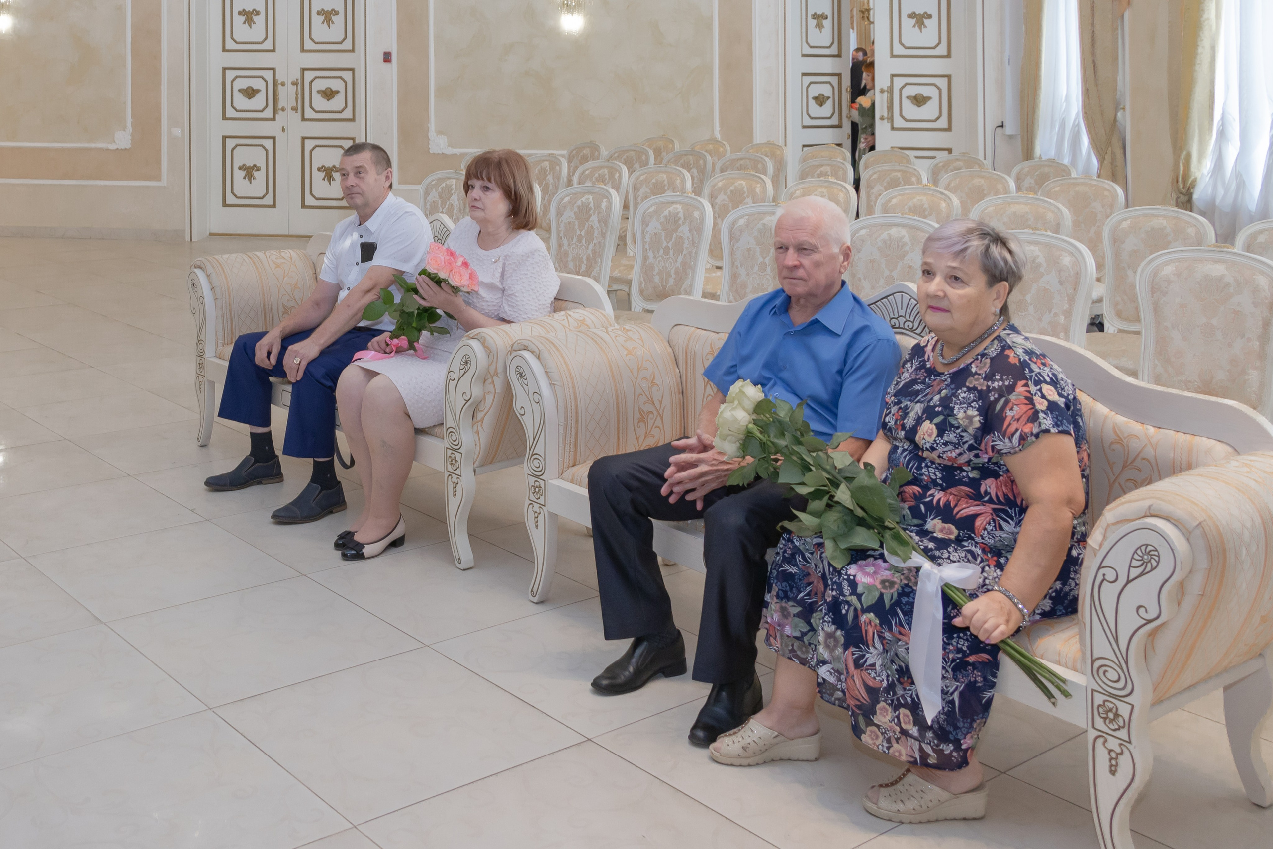 Родственники жениха и невесты сидят в ЗАГСе на торжественной церемонии регистрации брака