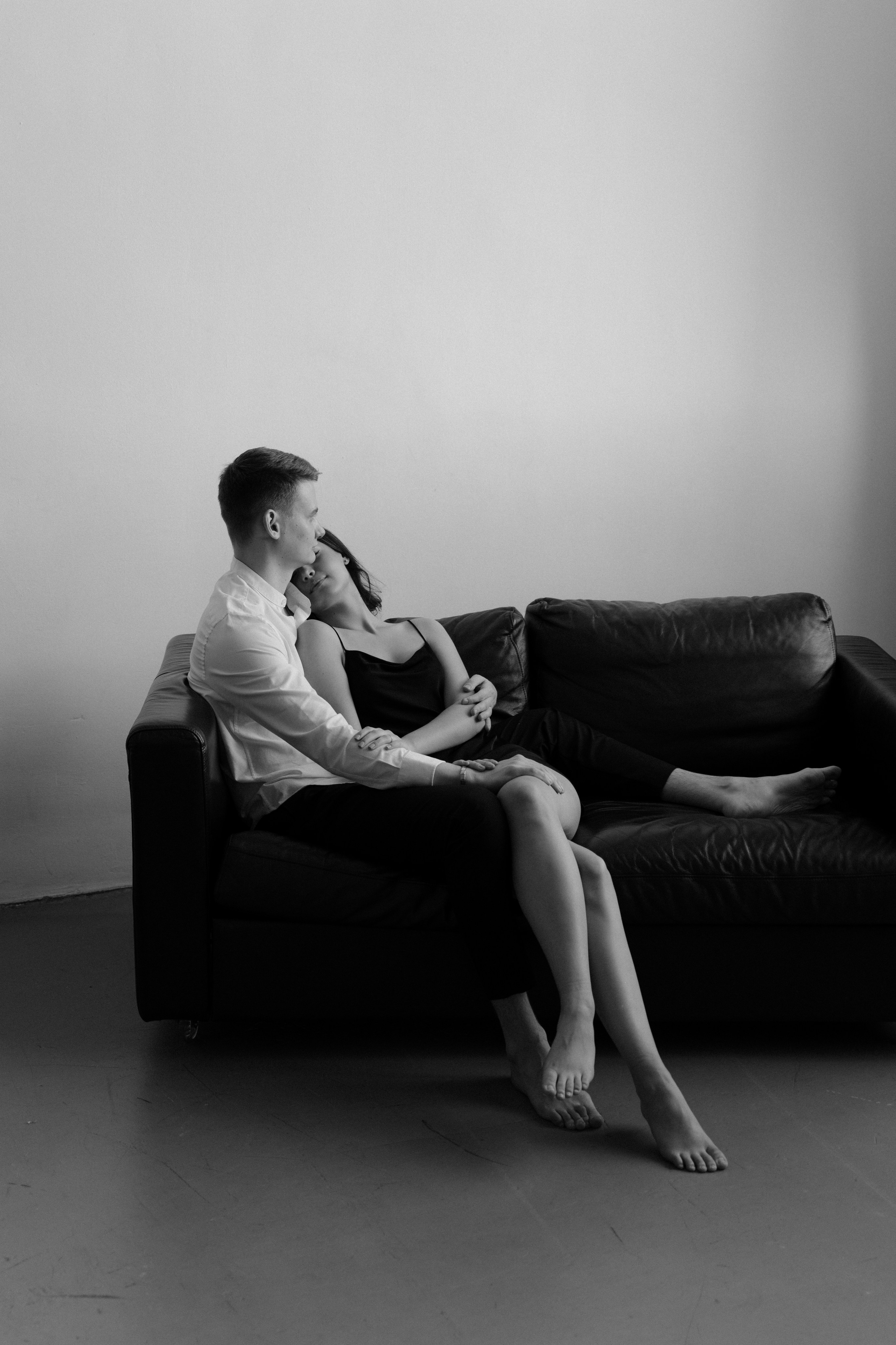 Пара лежит в фотостудии на диване и обнимается