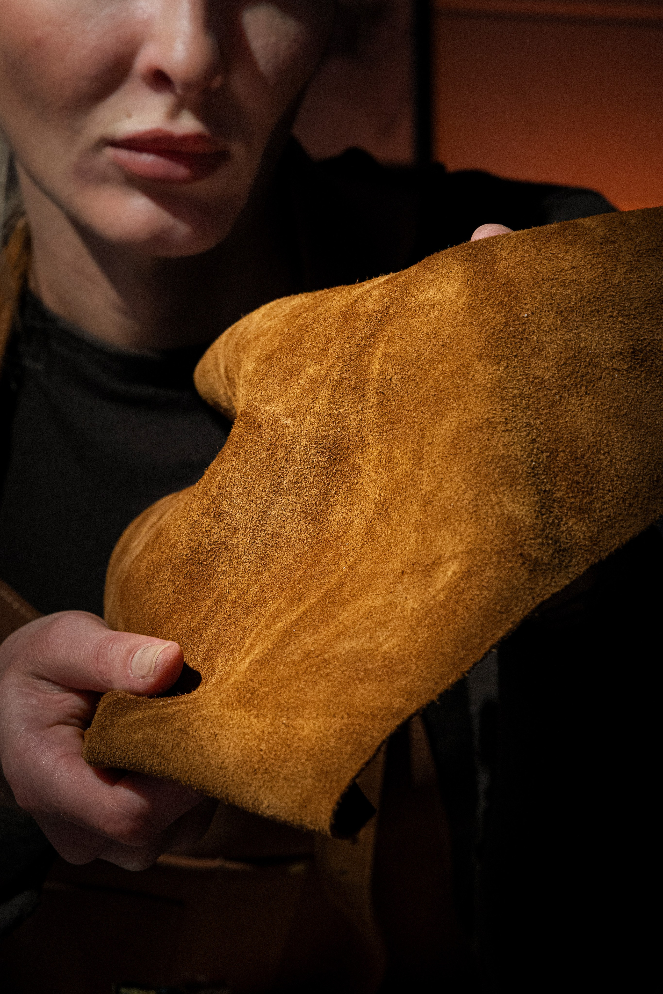 Девушка‑мастер аккуратно вырезает деталь из кожи профессиональным ножом.