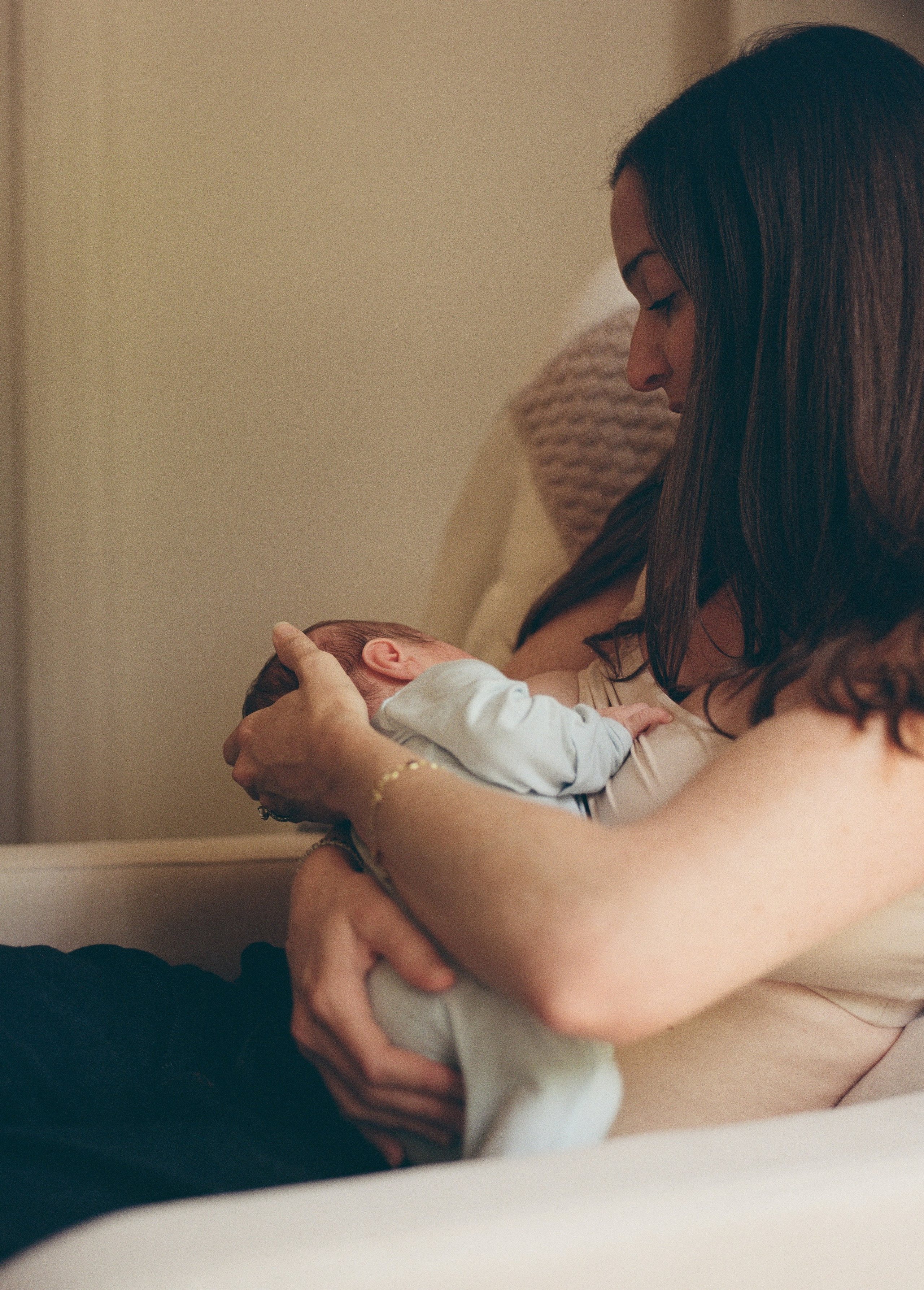 a candid film image of a woman breastfeeding her newborn baby in their nursery