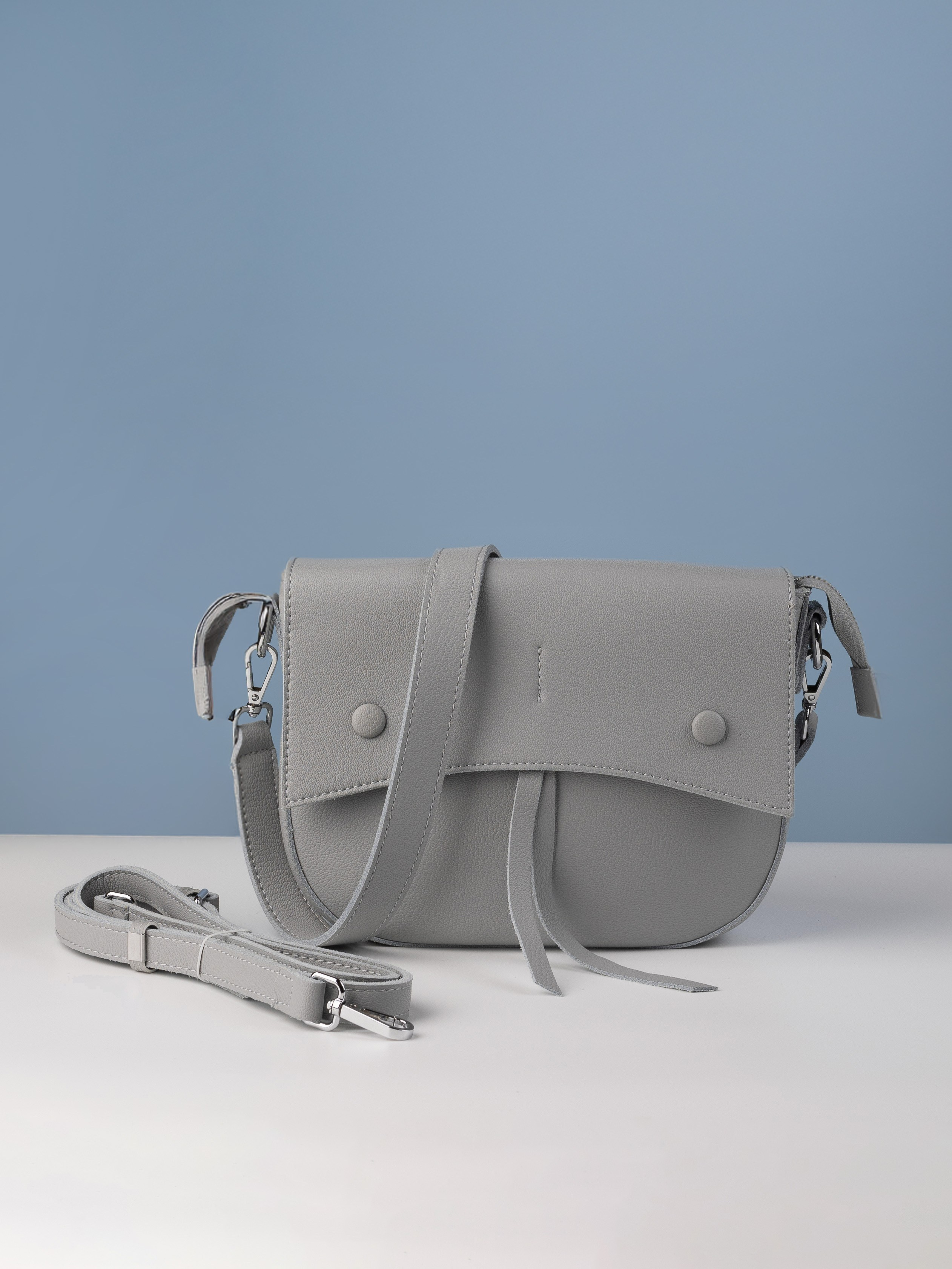 серая женская сумка  на голубом фоне